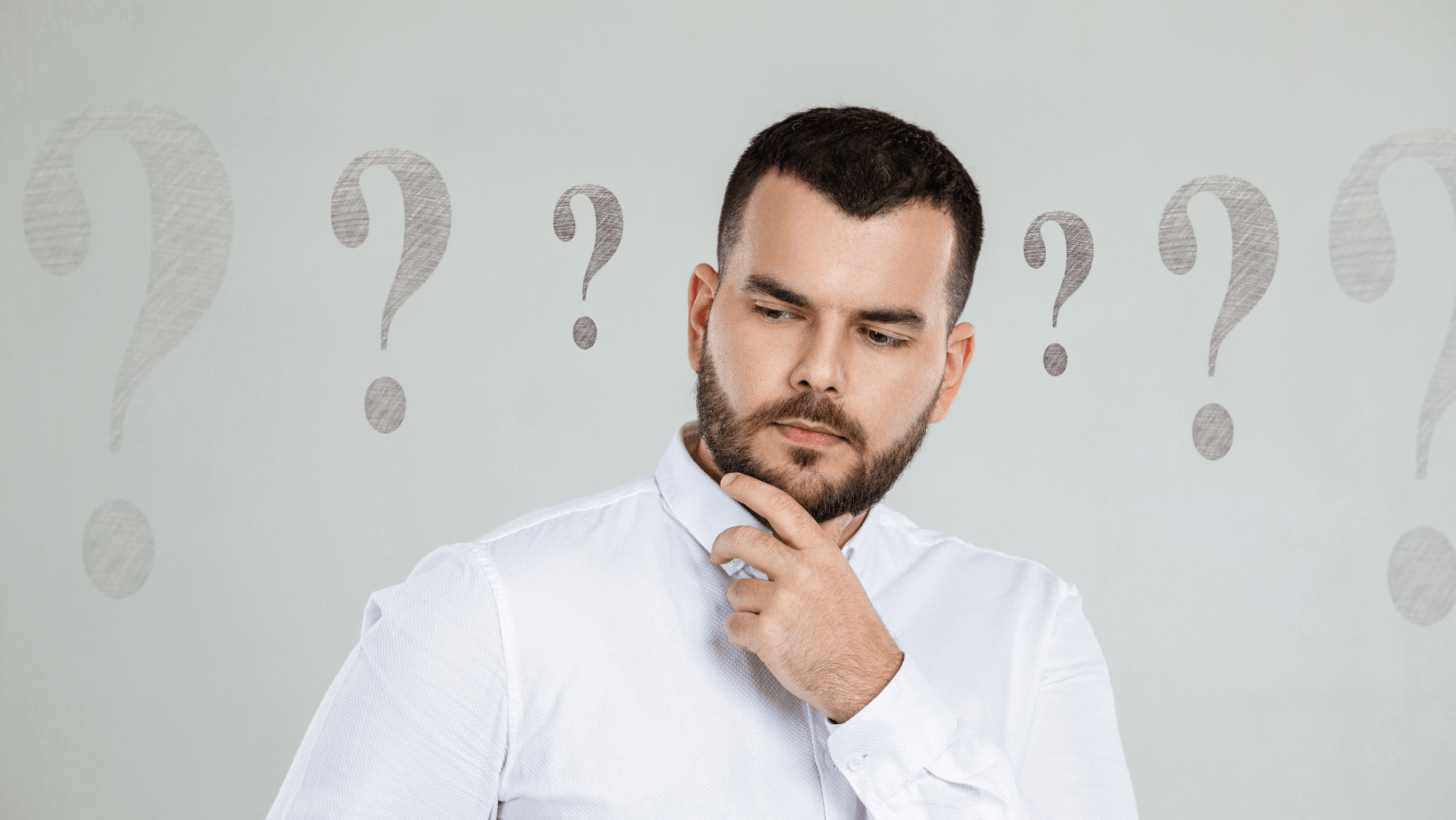 Man pondering with a thoughtful expression and question marks in the background, illustrating inquiries about ductless HVAC systems and their benefits.