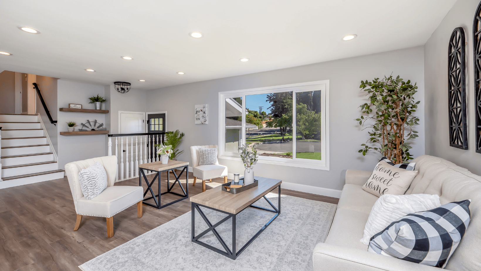 Modern living room with a cozy sofa, decorative pillows, and stylish furniture, showcasing a bright interior with natural light from large windows, plants, and a welcoming atmosphere, relevant to home comfort and HVAC discussions.