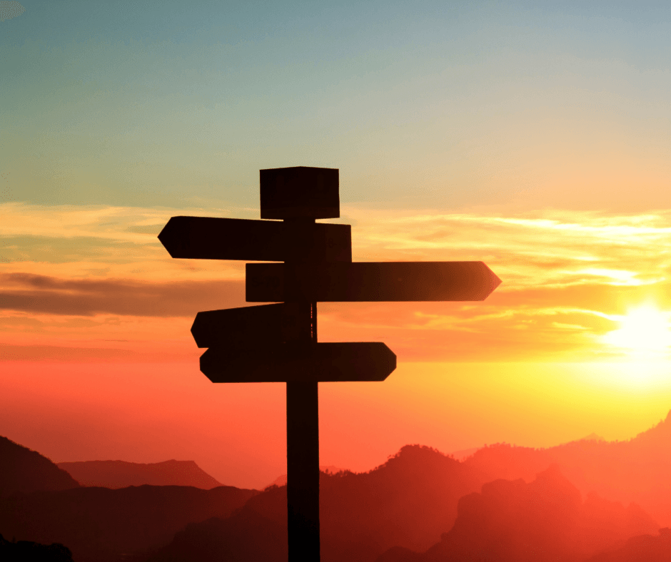 Silhouette of a directional signpost against a vibrant sunset sky, symbolizing choices and guidance in HVAC system replacement decisions.