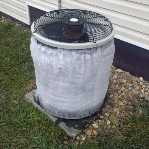 Frozen outdoor HVAC unit covered in ice, illustrating common HVAC issues related to freezing, relevant to HVAC maintenance and repair services.