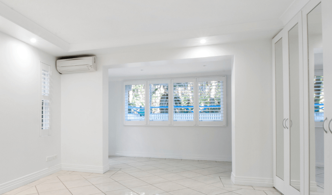 Ductless mini-split air conditioning unit mounted on a white wall in a bright, modern room with large windows and tiled flooring, illustrating HVAC installation for residential spaces.