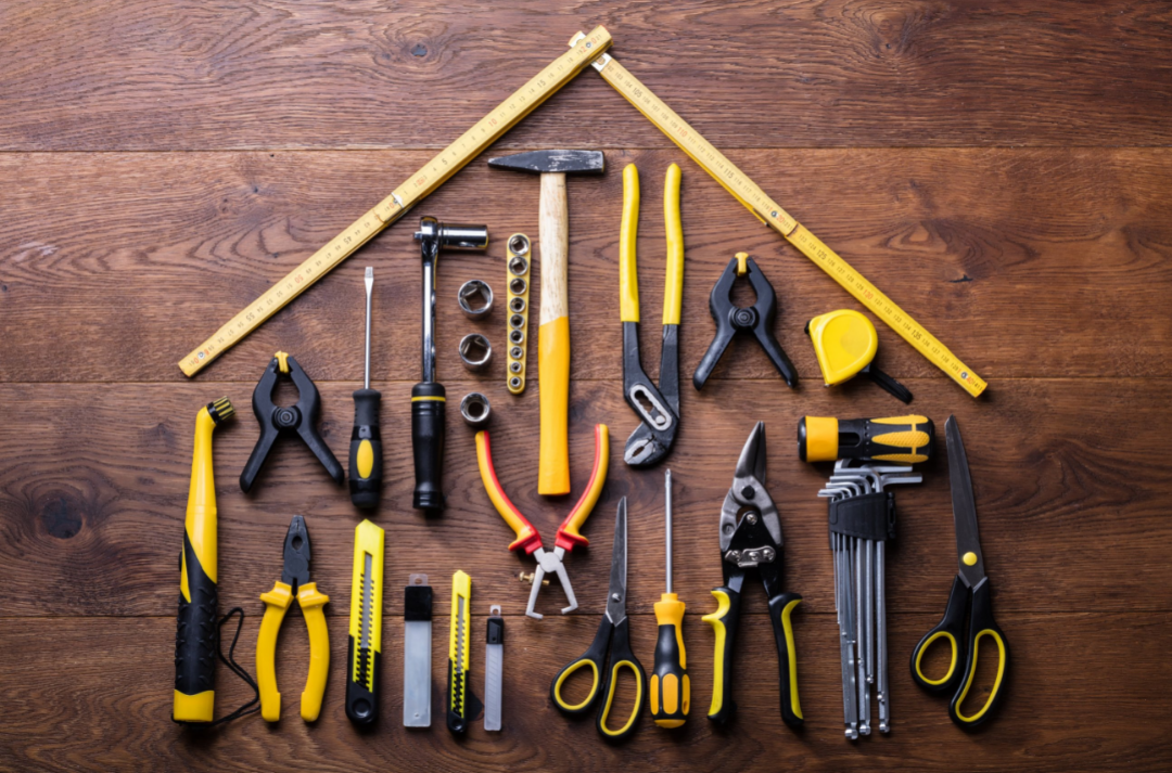Tools arranged in a house shape on wooden background, including pliers, screwdrivers, hammers, measuring tape, and scissors, symbolizing HVAC repair and maintenance.