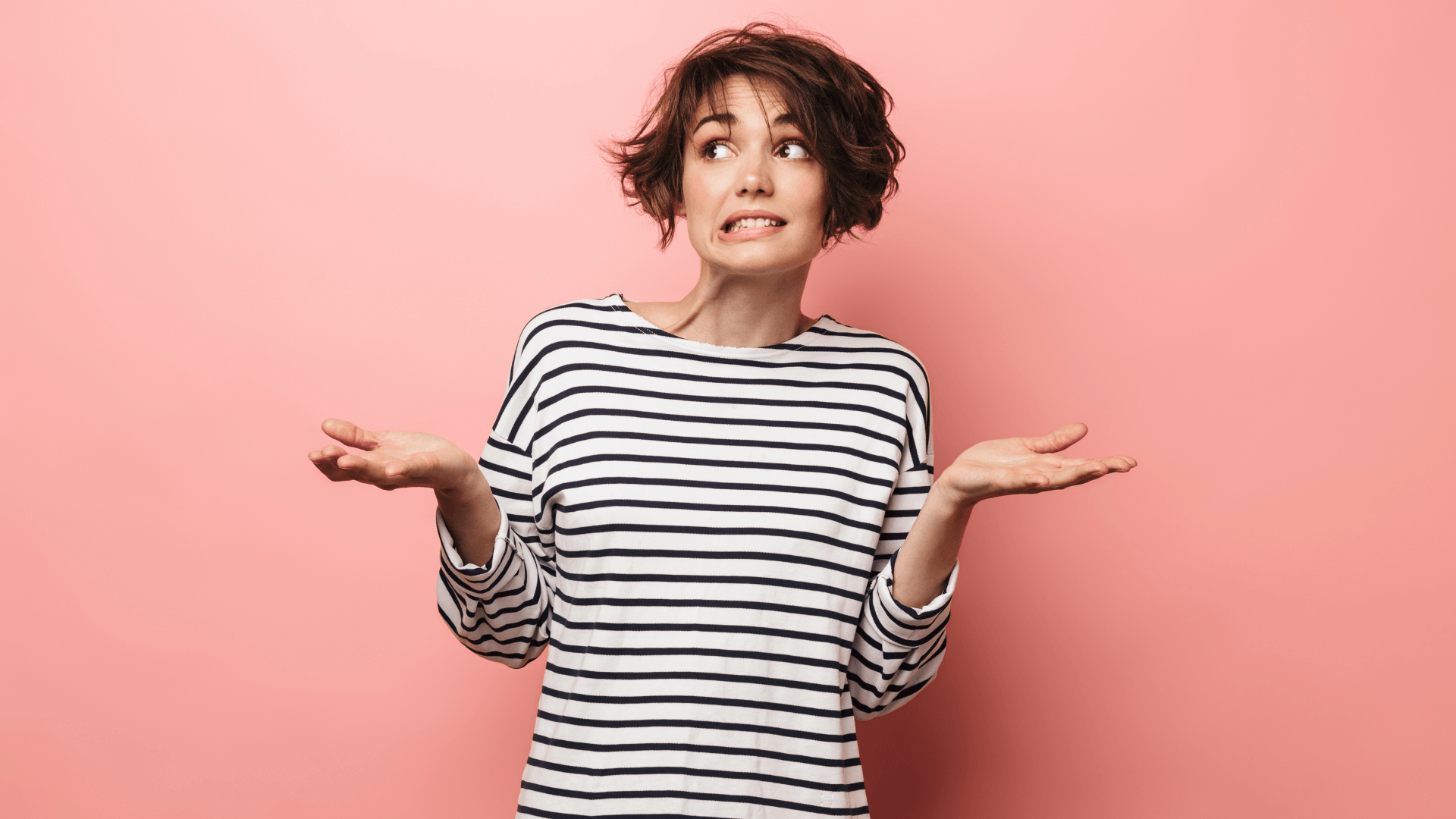 Woman in striped shirt with a confused expression, shrugging her shoulders, against a pink background, symbolizing uncertainty or seeking HVAC solutions.