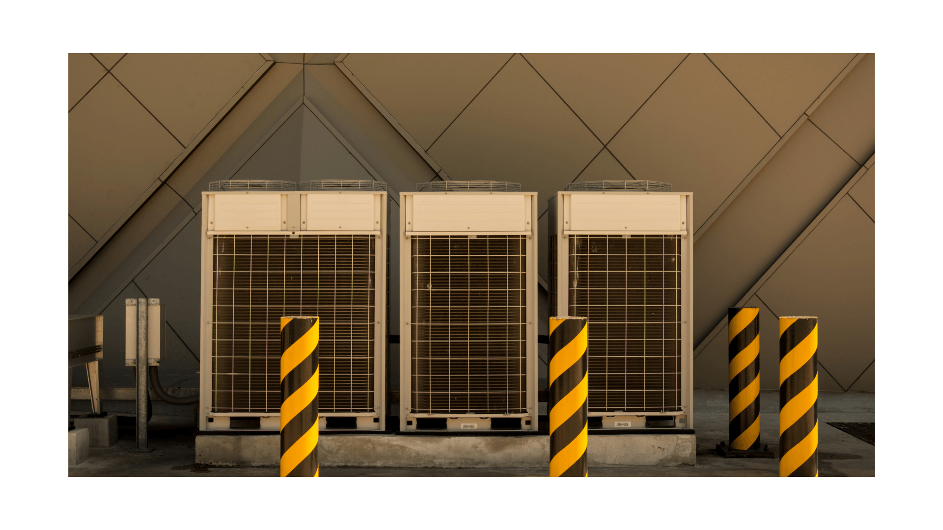 Commercial HVAC system with three outdoor heat pump units beside striped safety poles, emphasizing energy efficiency and climate control for businesses.