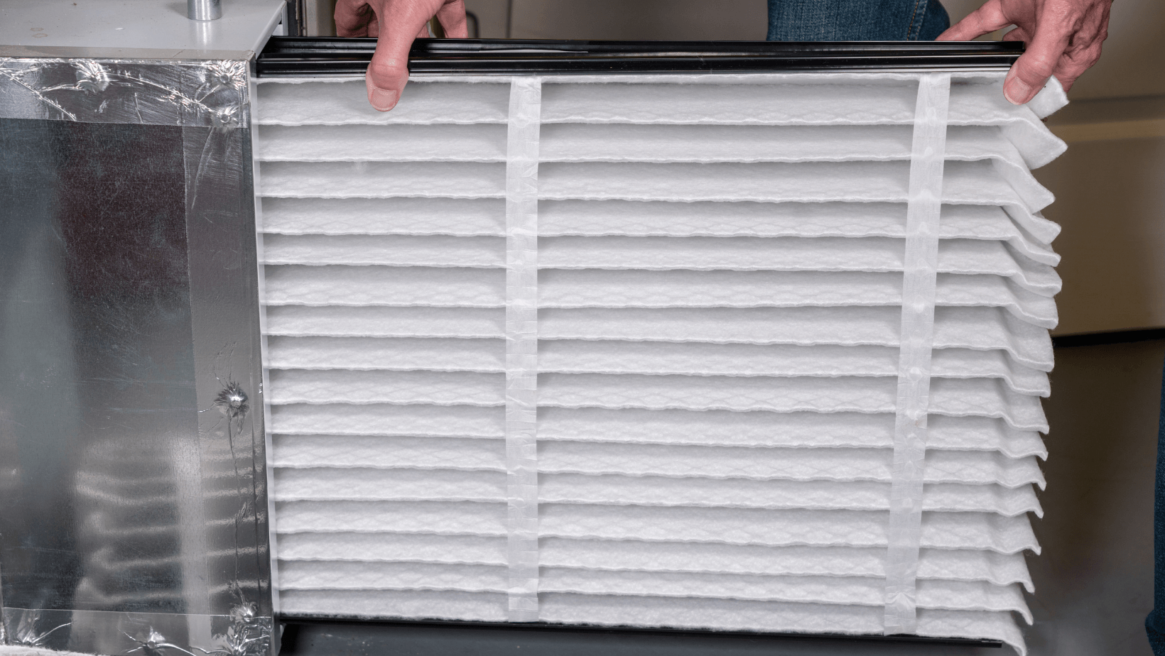 Person holding an air filter for HVAC system installation, emphasizing air quality maintenance and energy efficiency.