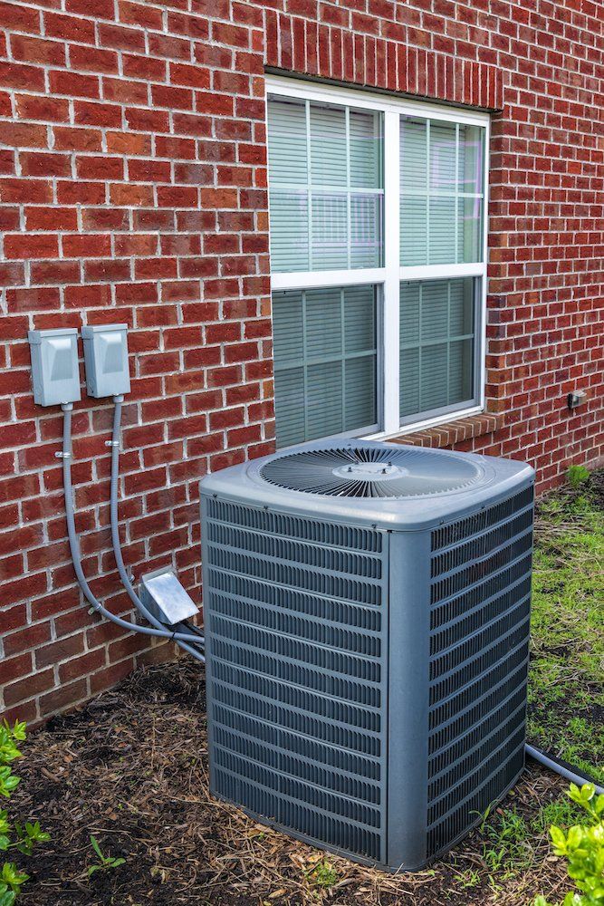 Air conditioning unit installed outside a brick house, showcasing HVAC system for residential heating and cooling services in Beaverton.