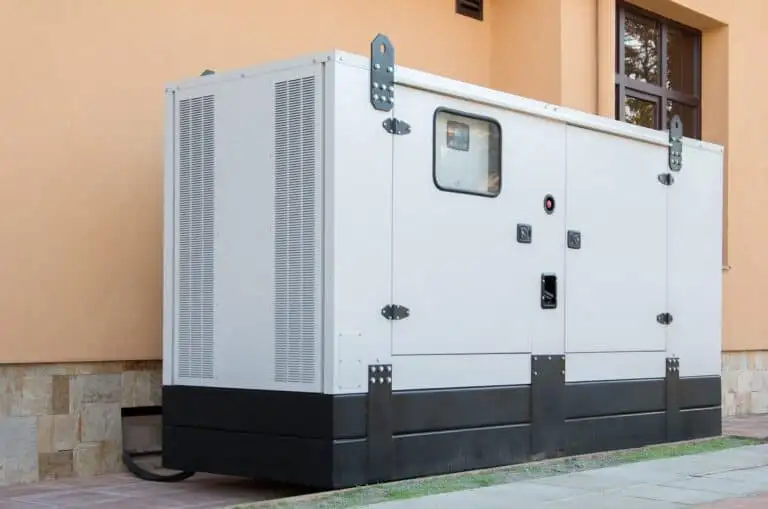 A large white standby generator is installed on a concrete pad outside a residential building