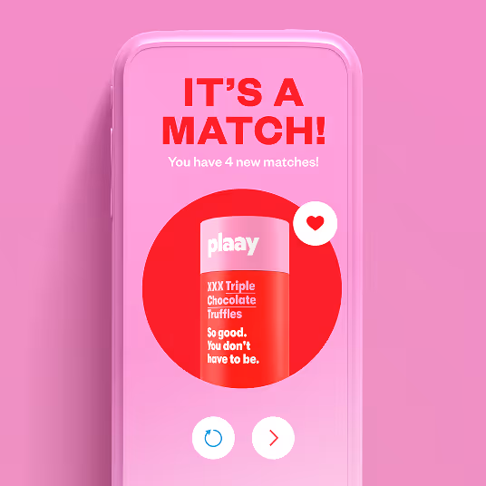 Smartphone screen with a pink background showing 'IT'S A MATCH! You have 4 new matches!' and an image of a red and pink plaay XXX Triple Chocolate Truffles container with a heart icon.