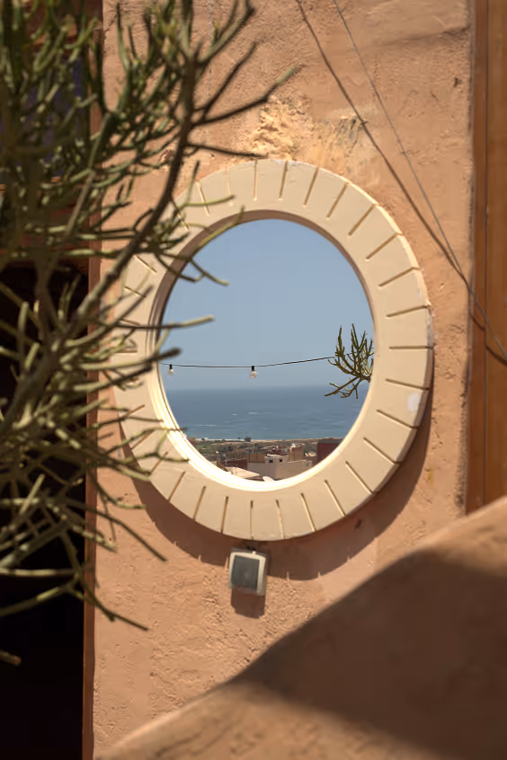 Round mirror reflecting ocean view at Salt House Morocco in Tamraght