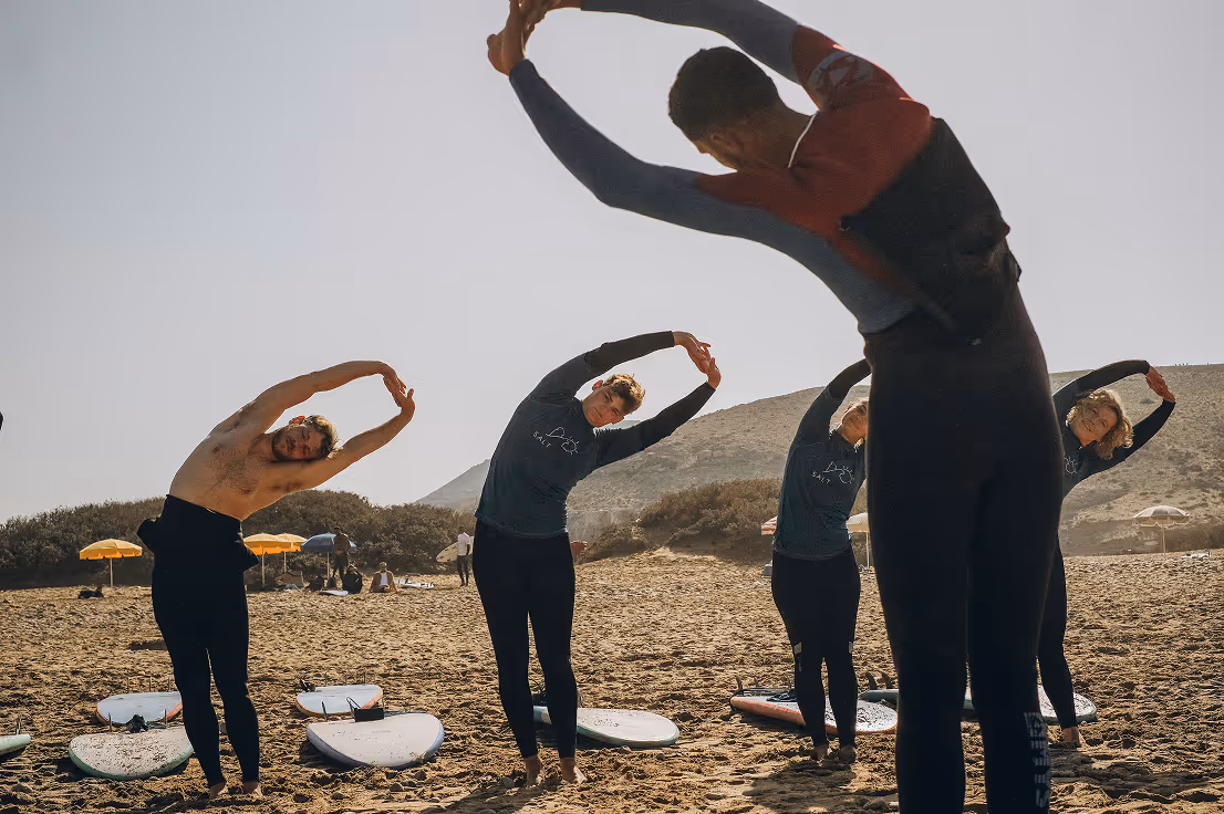 Beginner surf lesson warm-up on the beach in Taghazout, Morocco