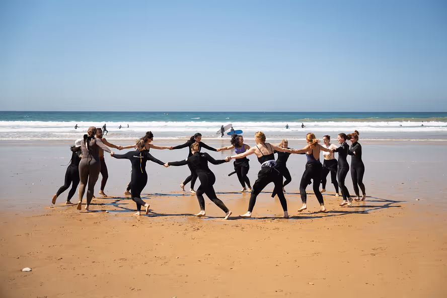Surf camp group doing warm-up exercises on the beach in Tamraght Morocco