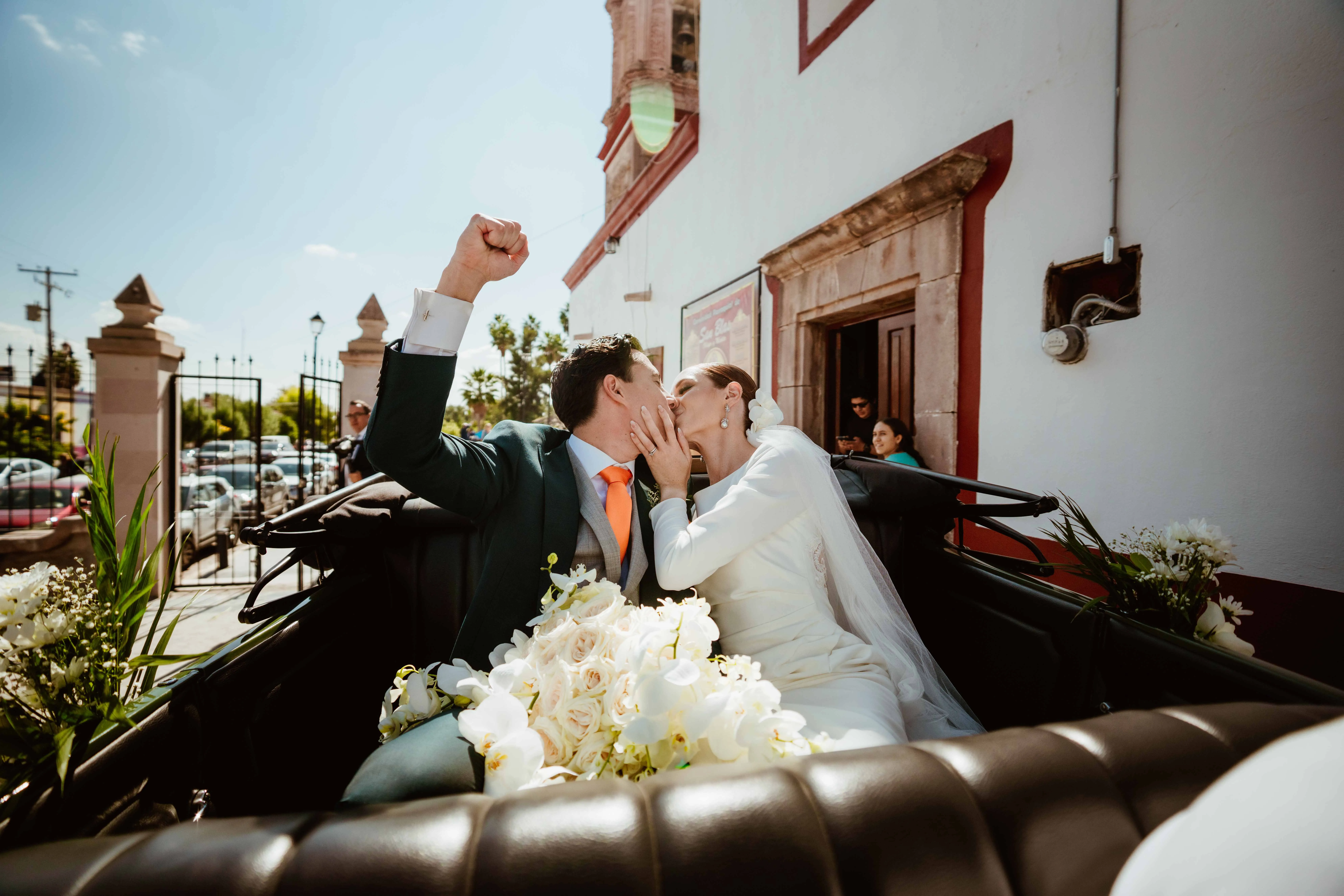 Beso de los novios en un coche descapotable al salir de su boda