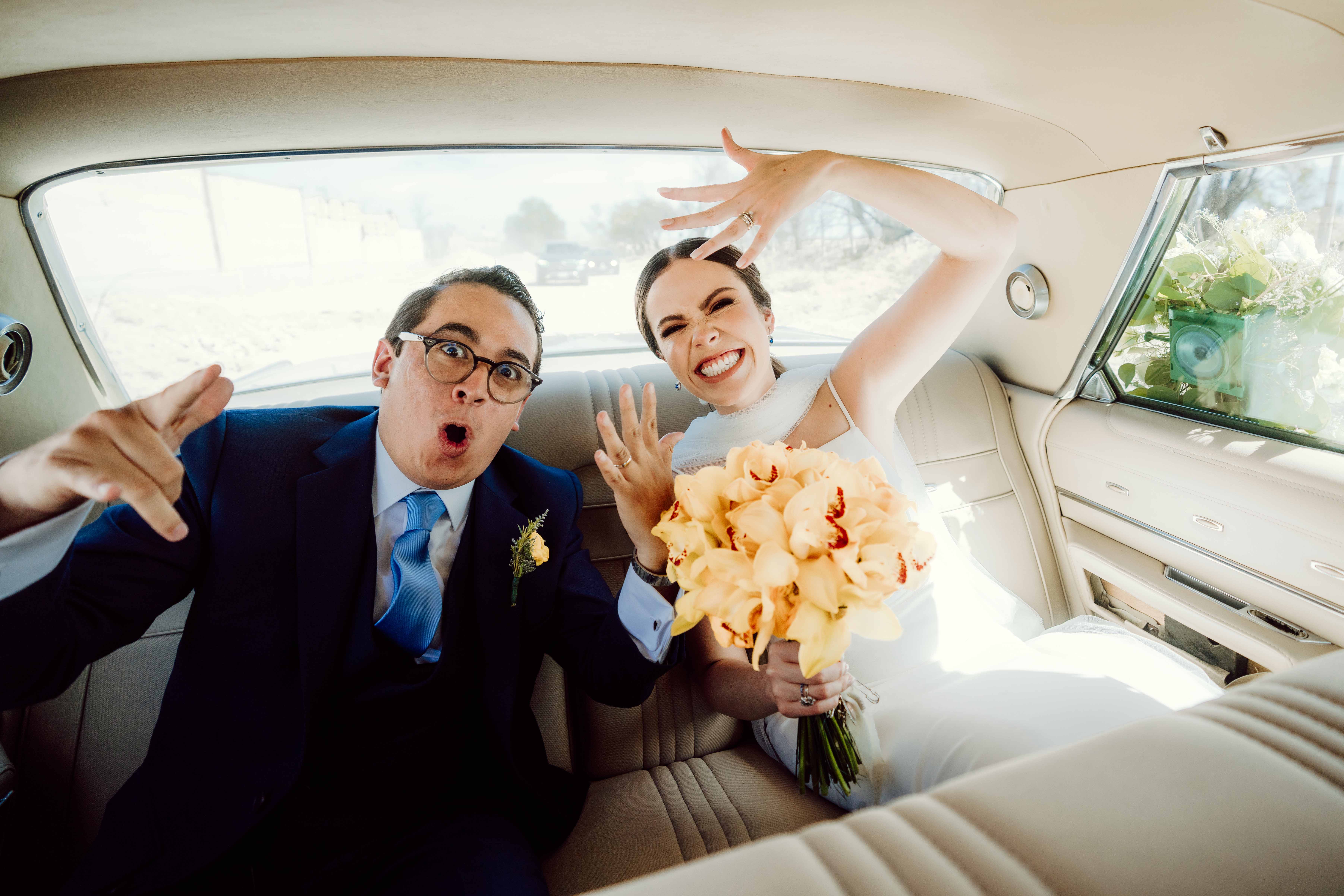 Novios celebrando dentro de un coche y mostrando sus anillos de boda