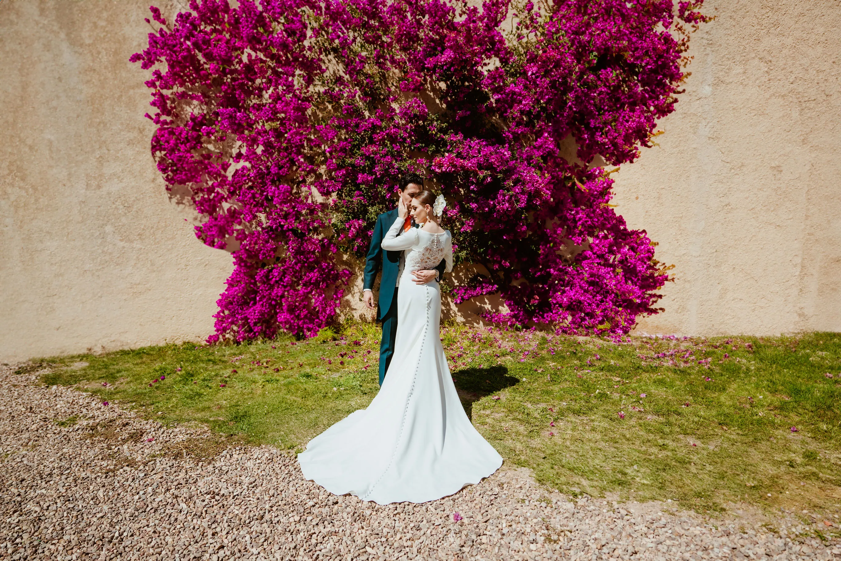Retrato de pareja de recién casados frente a una bugambilia en flor