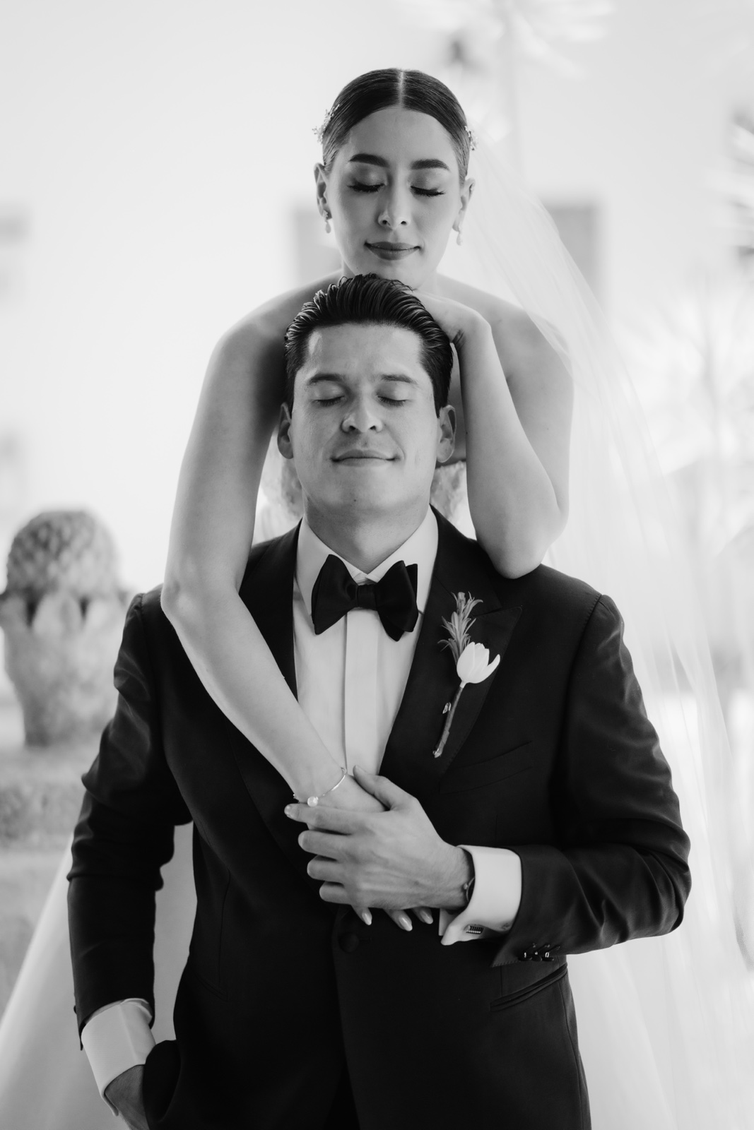 Ali abraza a Jairo por detrás; retrato de boda en blanco y negro