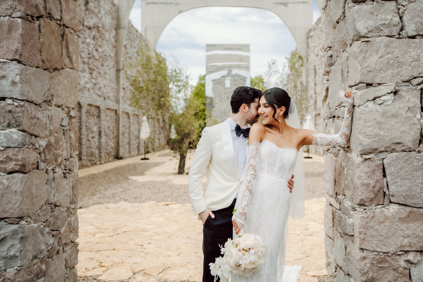 Mariana y Andrés juntos entre muros y arcos de piedra durante su boda
