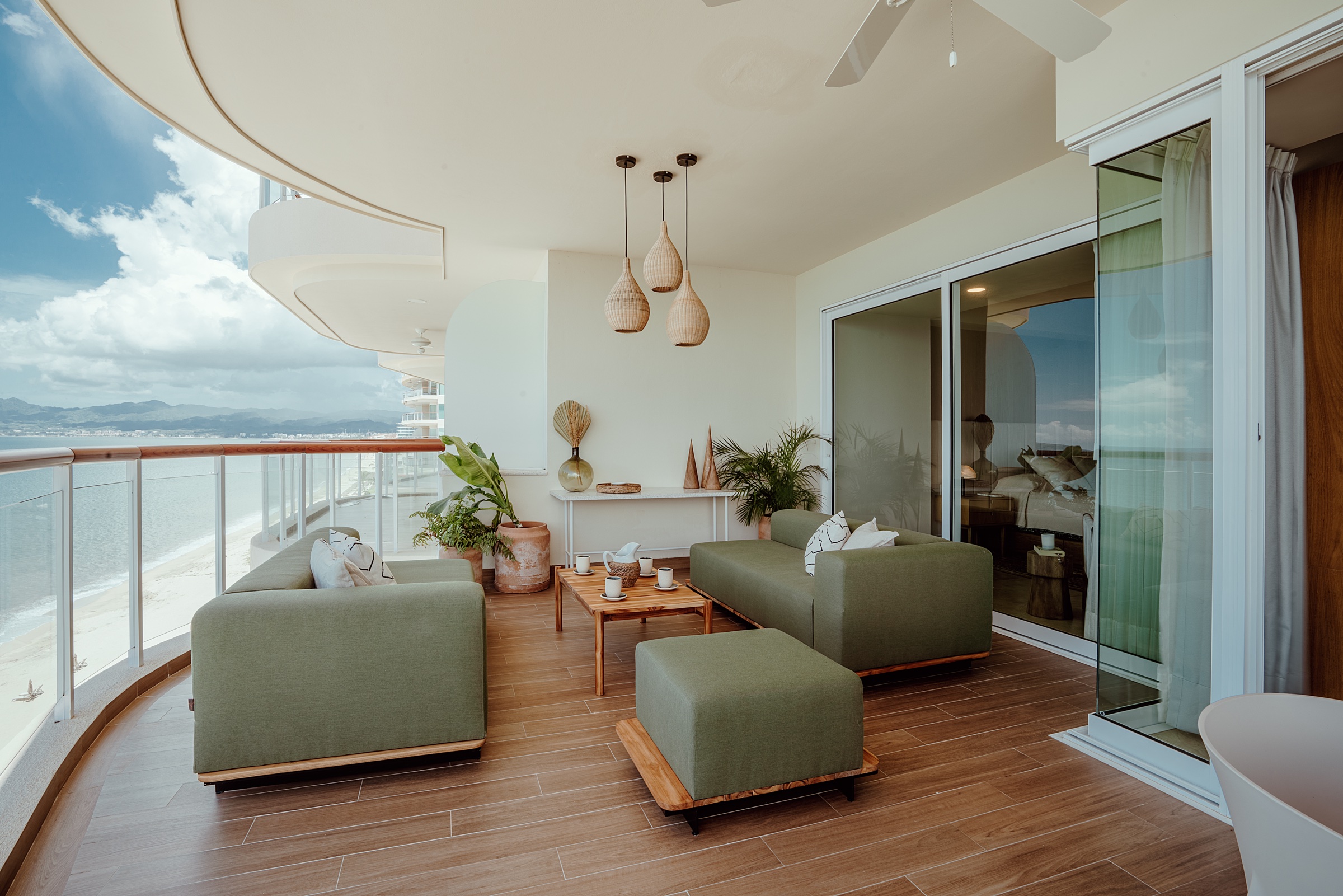 terraza frente al mar con muebles verdes y piso de madera