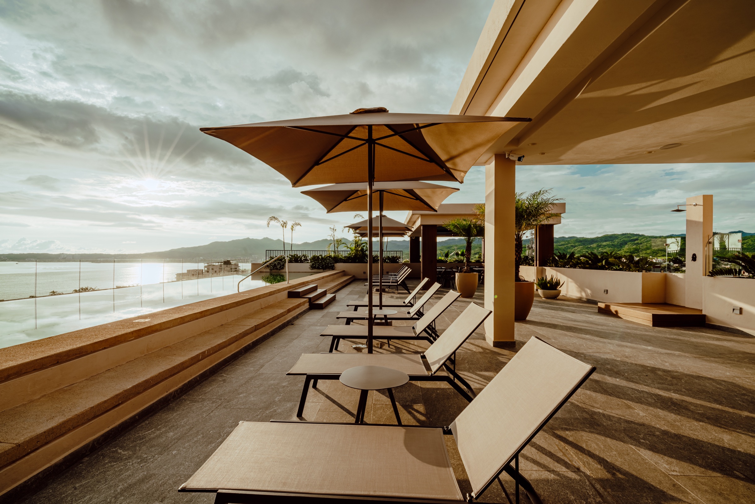 terraza con camastros y sombrillas frente al mar al atardecer