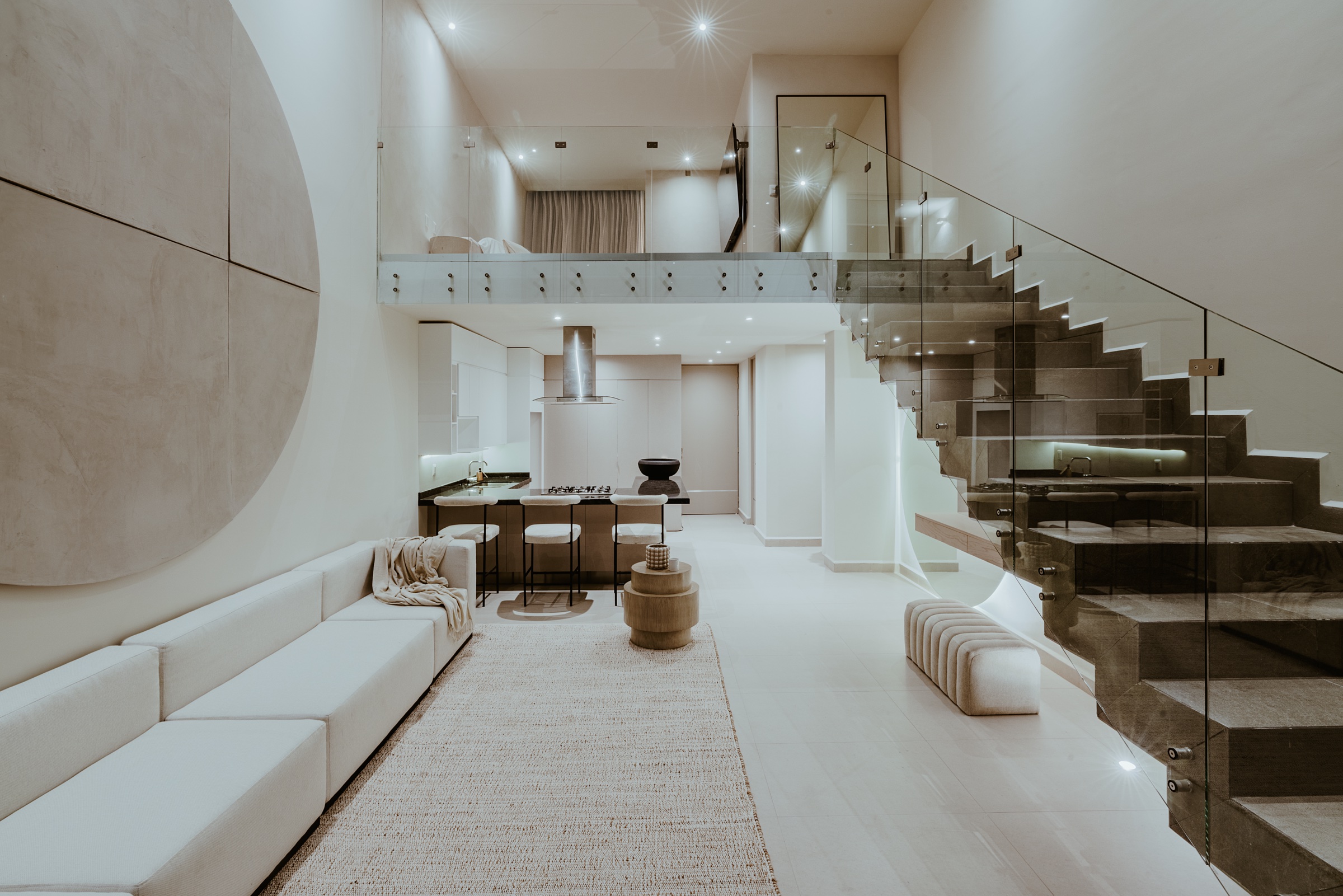 sala de doble altura con escalera y barandal de cristal