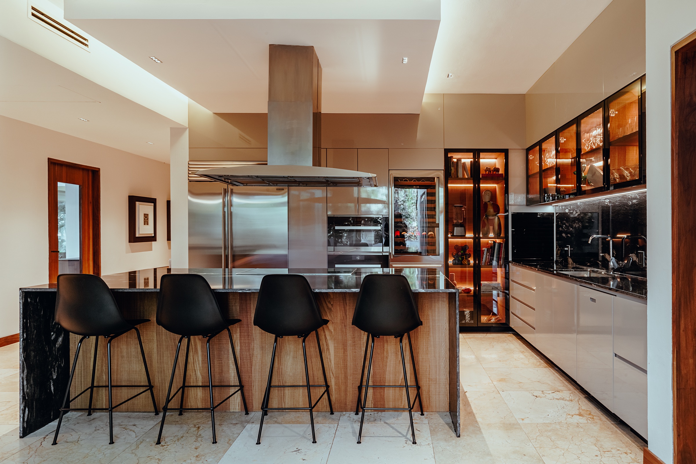 fotografía de interiores de una cocina con isla, bancos negros y cava