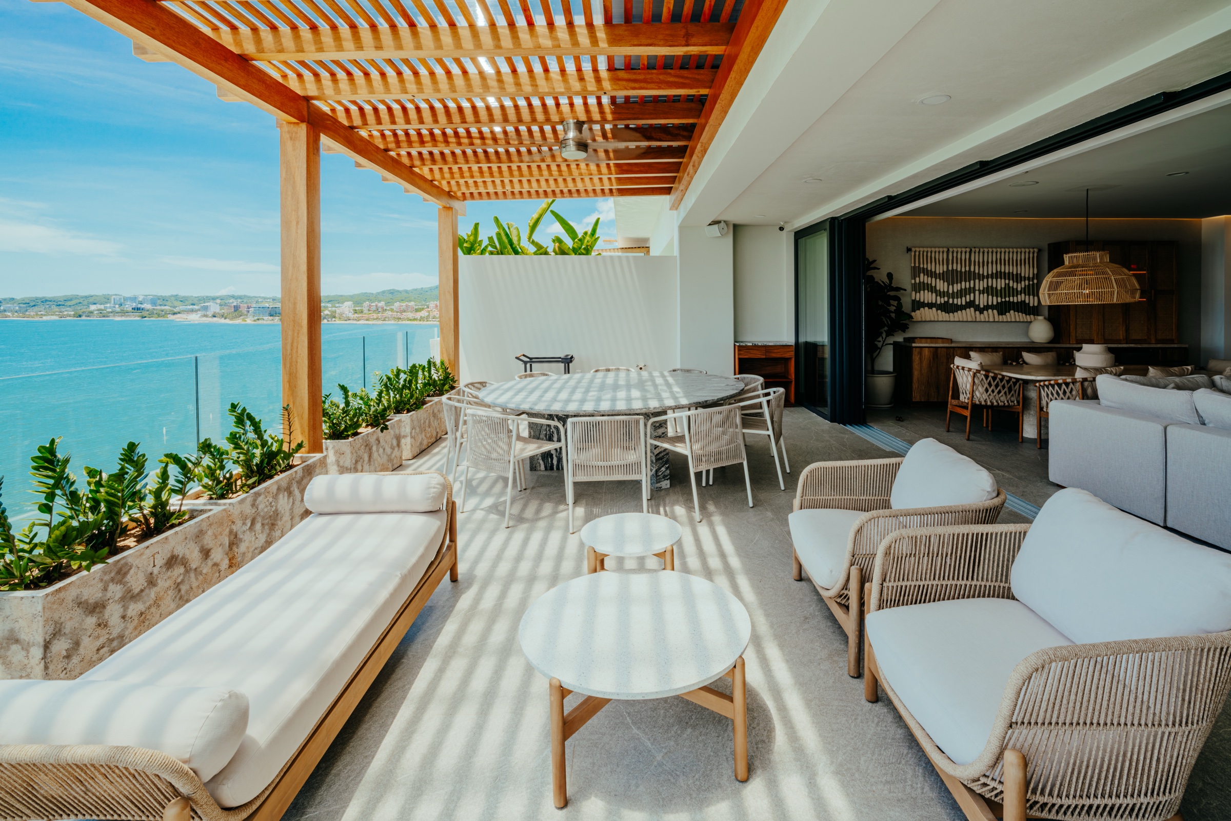 terraza con pérgola de madera y comedor con vista al mar