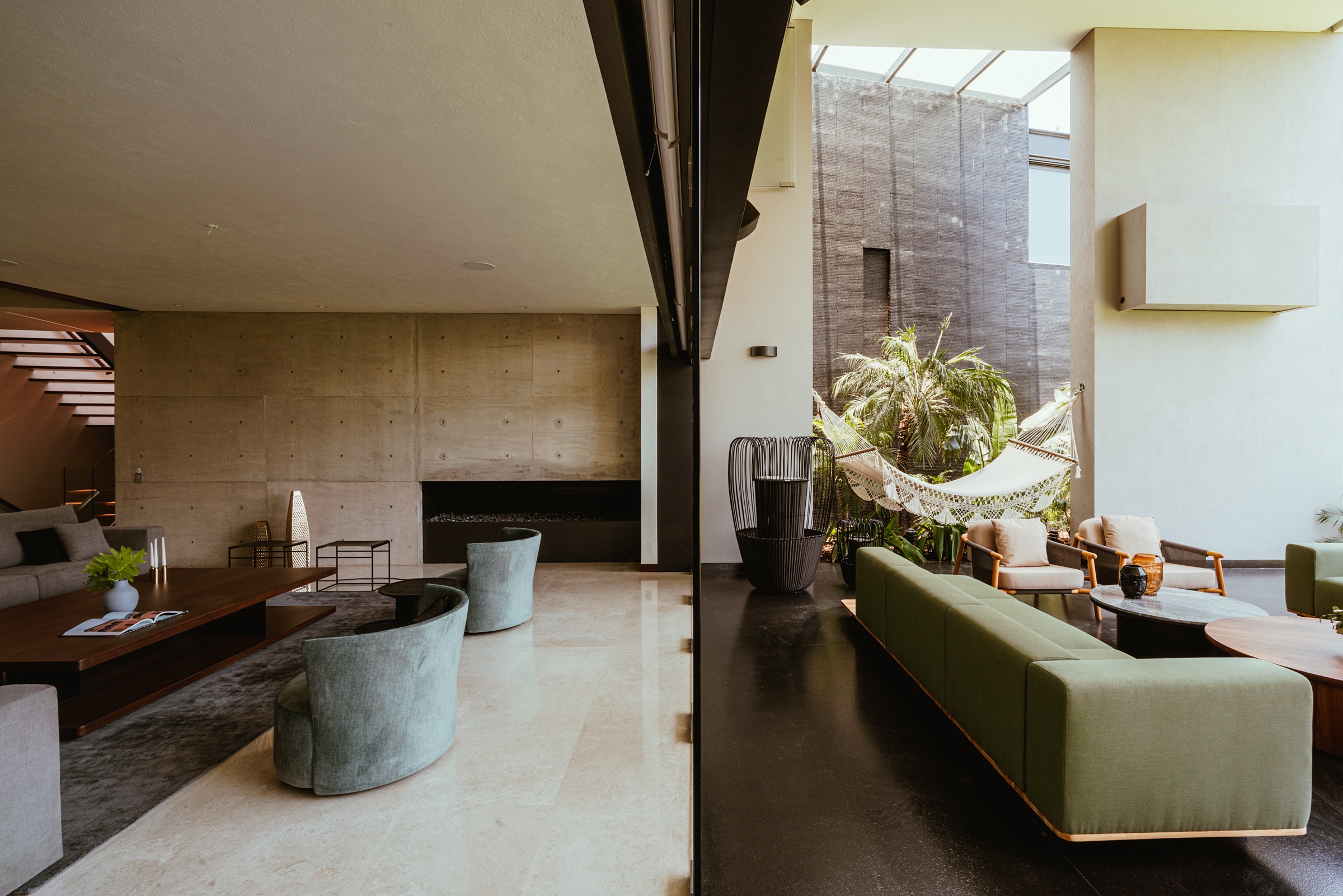 sala de doble altura abierta a un patio con vegetación y hamaca