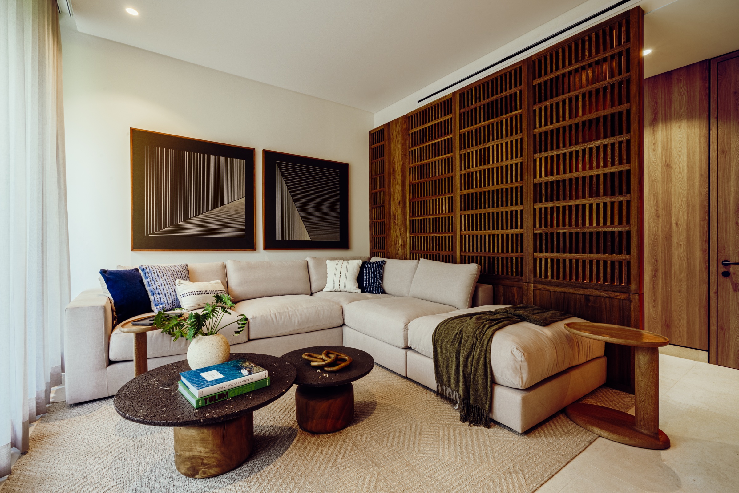 sala con sofá claro, mesas redondas y celosía de madera