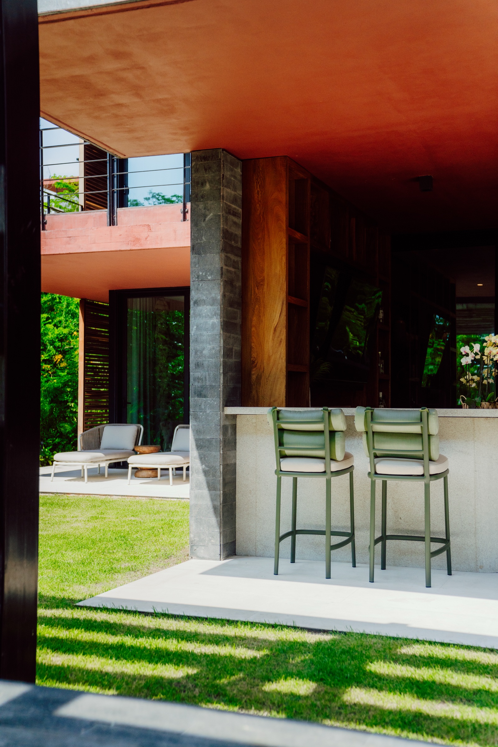 terraza con barra y bancos verdes junto al jardín
