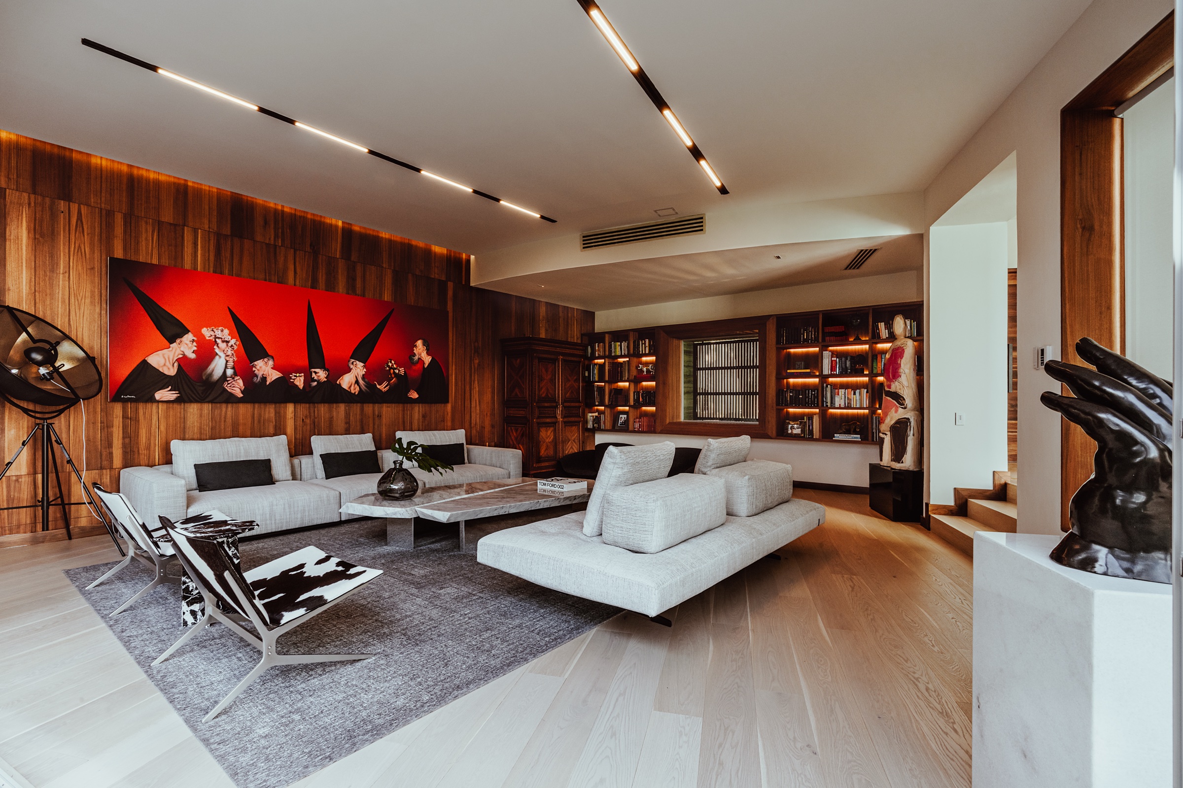 fotografía de interiores de una sala con sofás claros y muros de madera