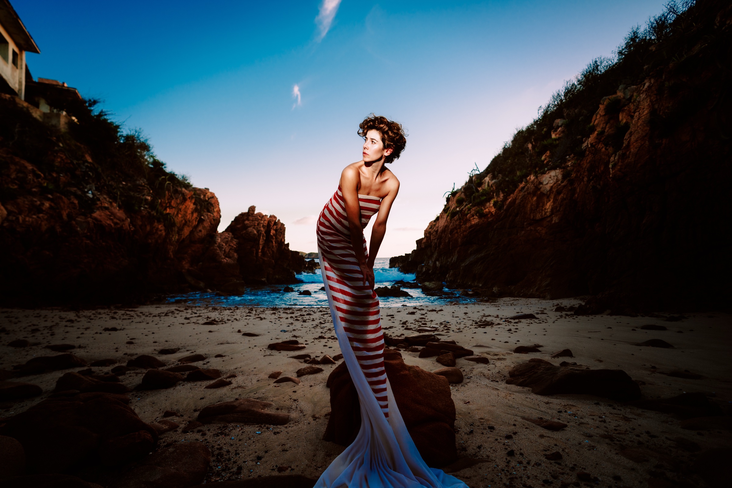 retrato editorial con tela de rayas en una playa entre rocas