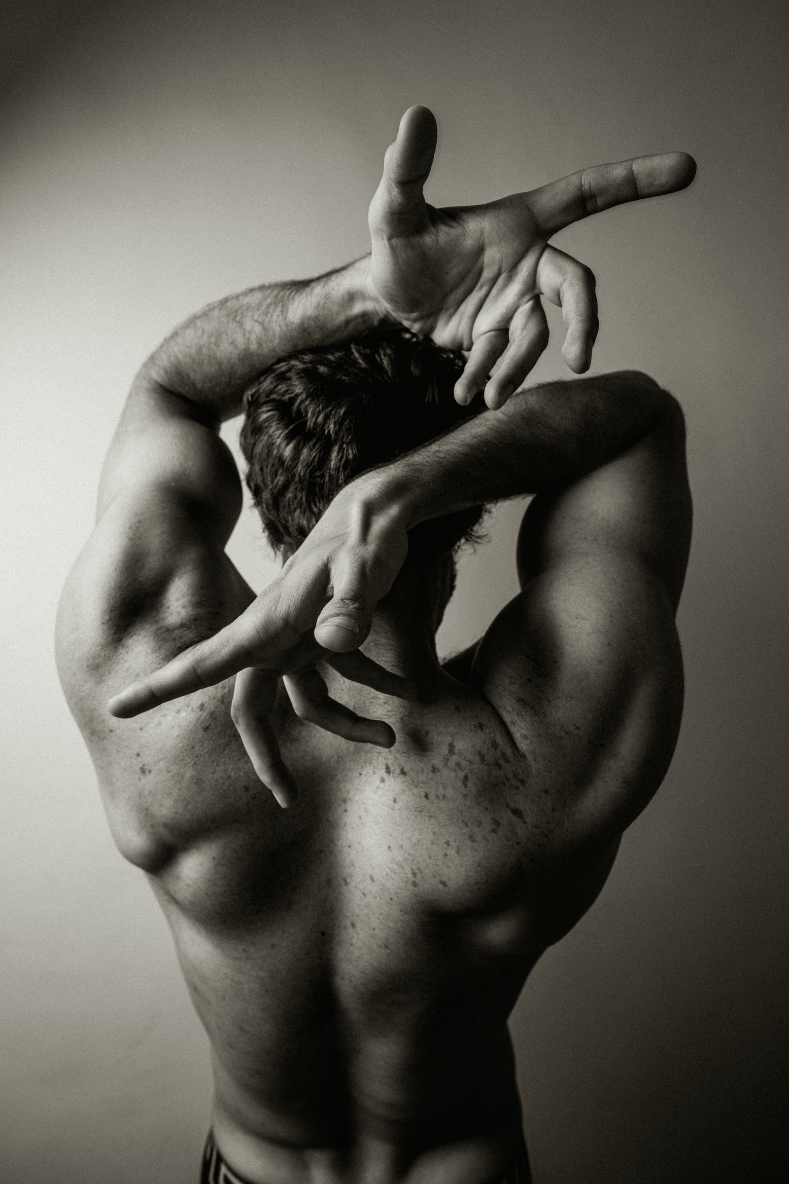 retrato en blanco y negro de un hombre con los brazos cruzados sobre la cabeza