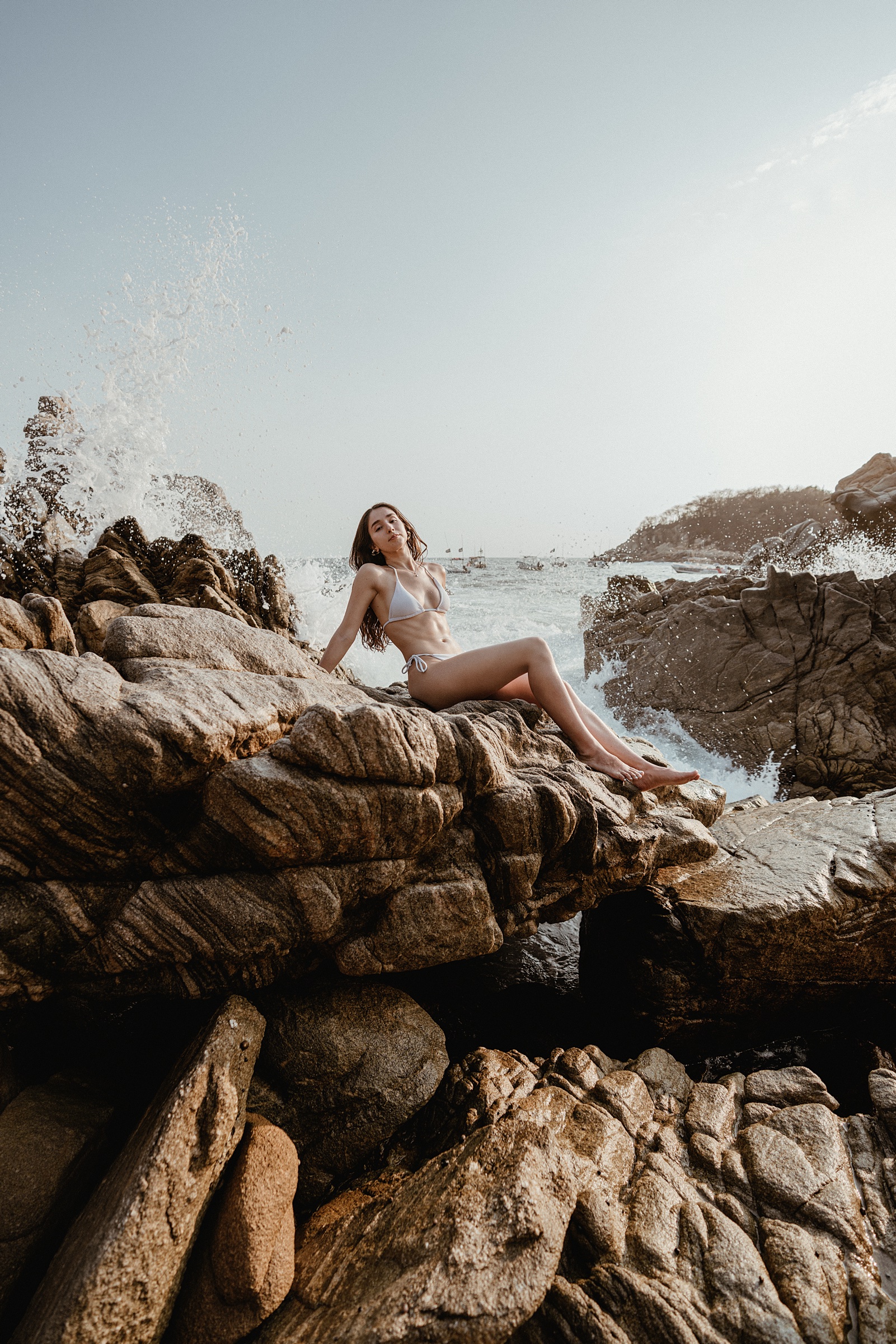 retrato editorial de una mujer sentada en rocas frente al mar