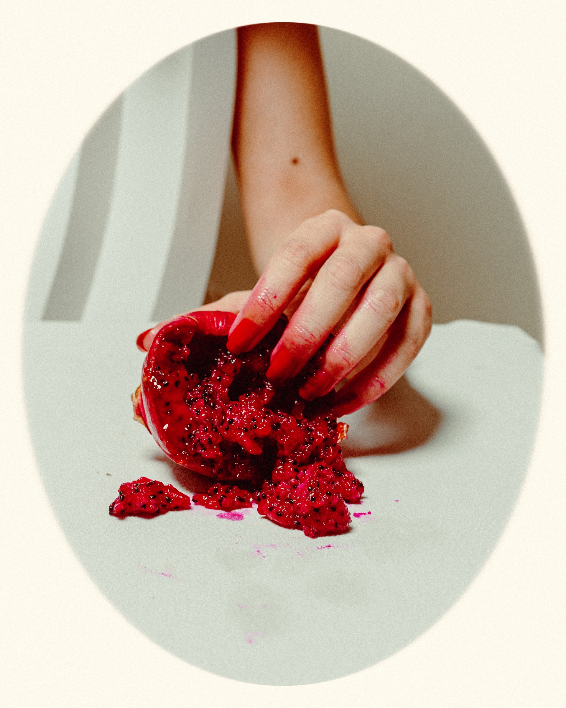 detalle editorial de una mano aplastando una pitaya roja