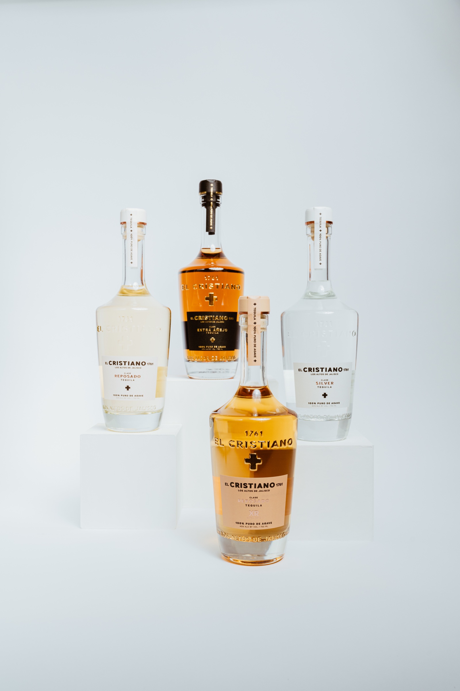 fotografía de producto de cuatro botellas de tequila El Cristiano sobre fondo claro