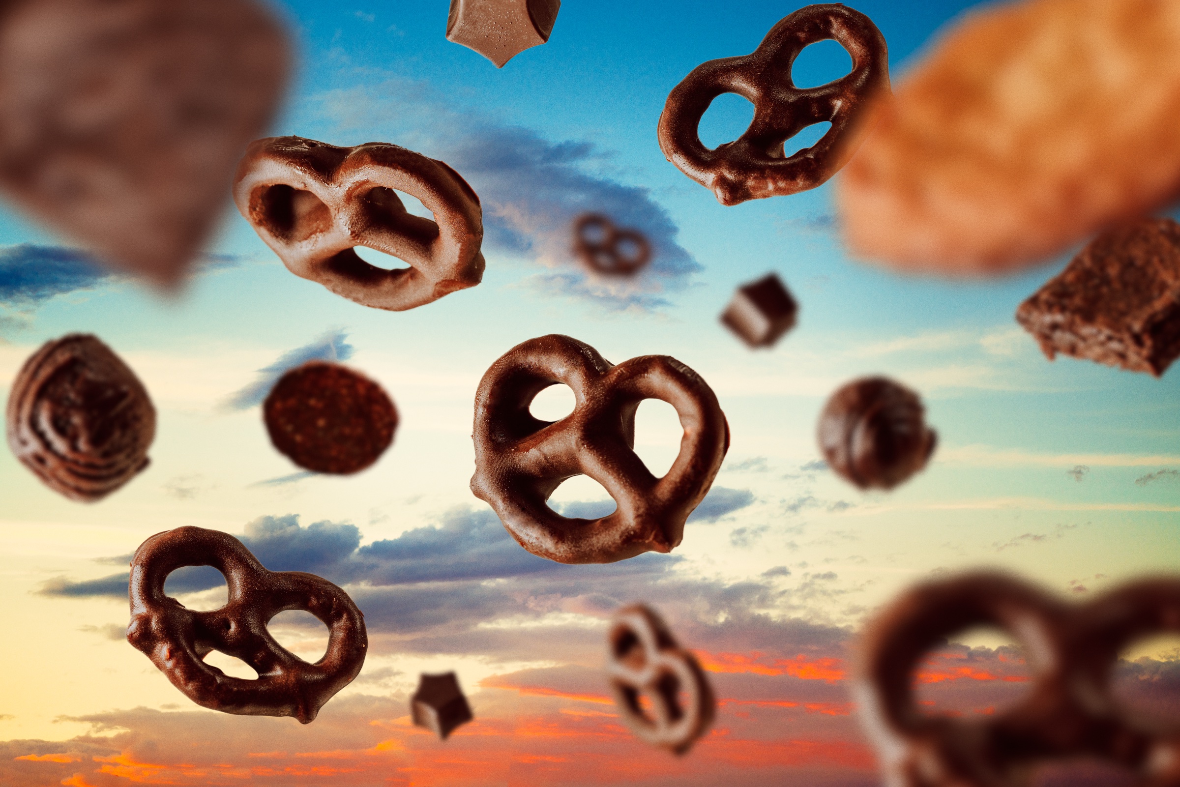 fotografía de producto con pretzels cubiertos de chocolate suspendidos ante un cielo de atardecer
