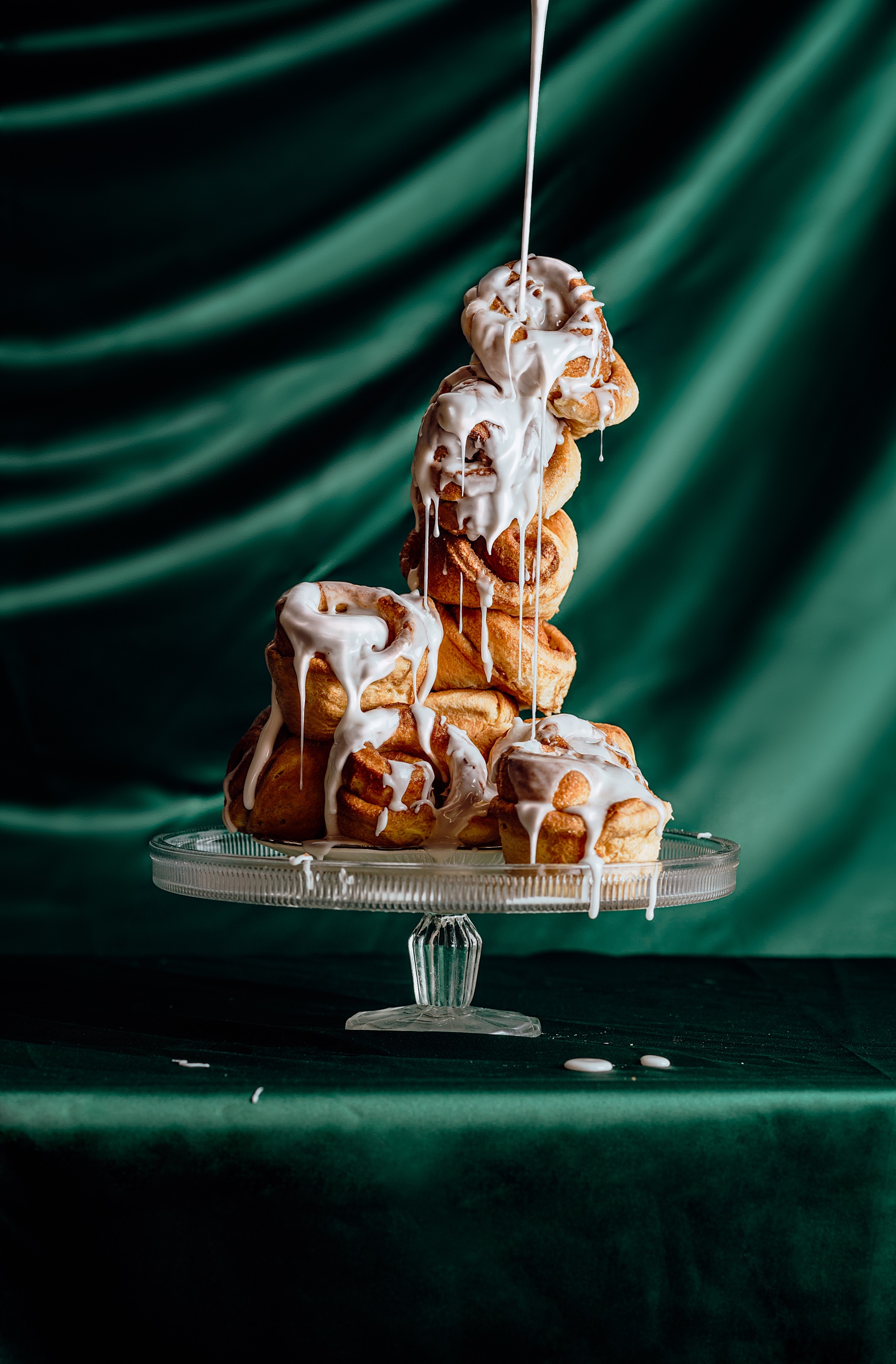 fotografía gastronómica de roles de canela con glaseado sobre tela verde