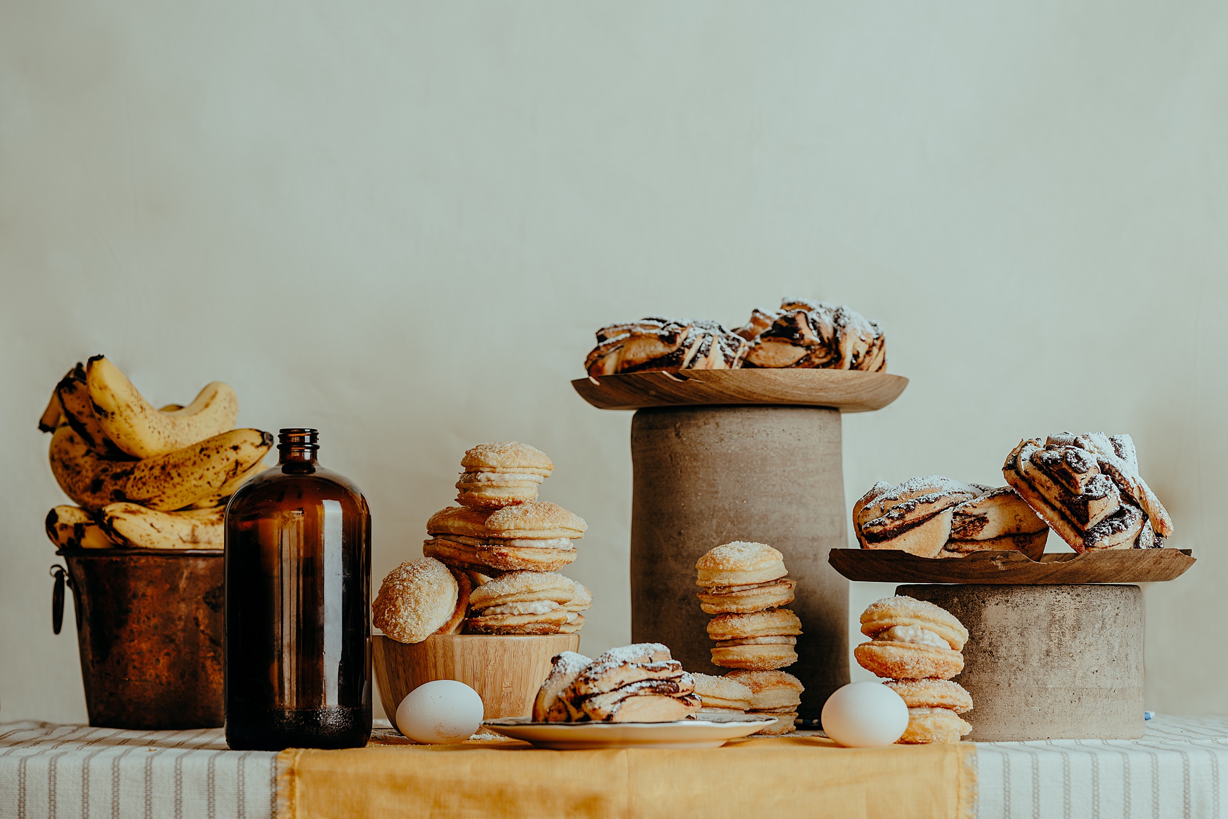 bodegón de pan dulce, plátanos, huevos y una botella sobre una mesa