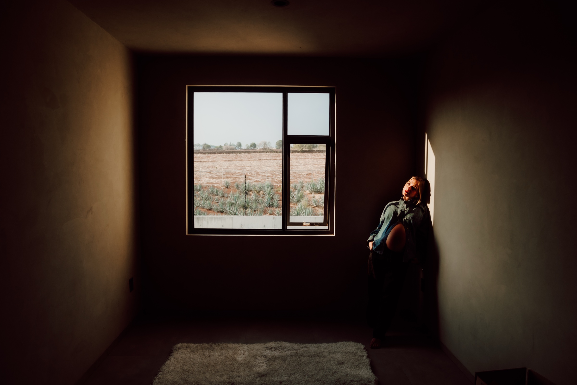 retrato de maternidad junto a una ventana en una habitación oscura