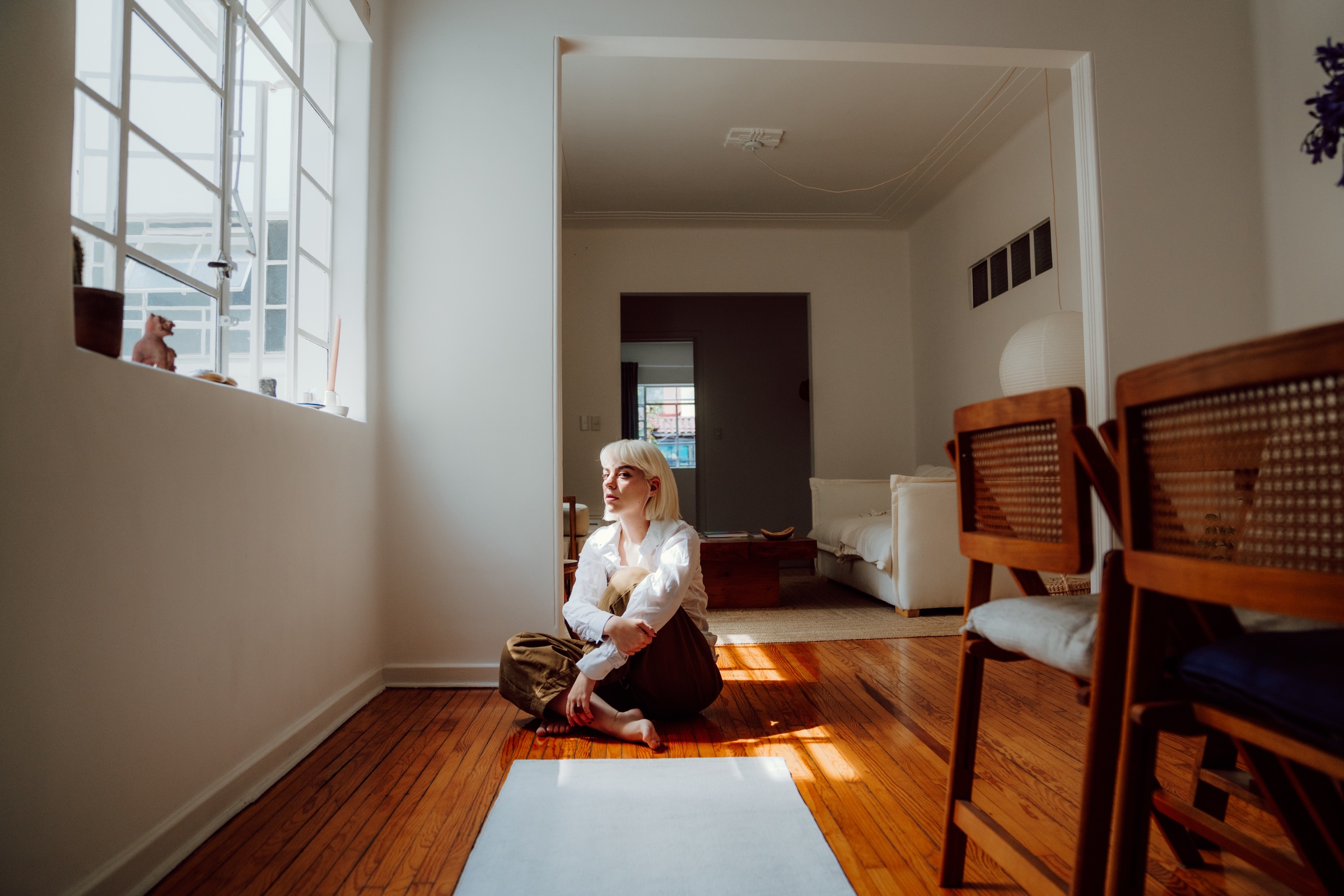 retrato de una mujer sentada junto a una ventana en un interior luminoso