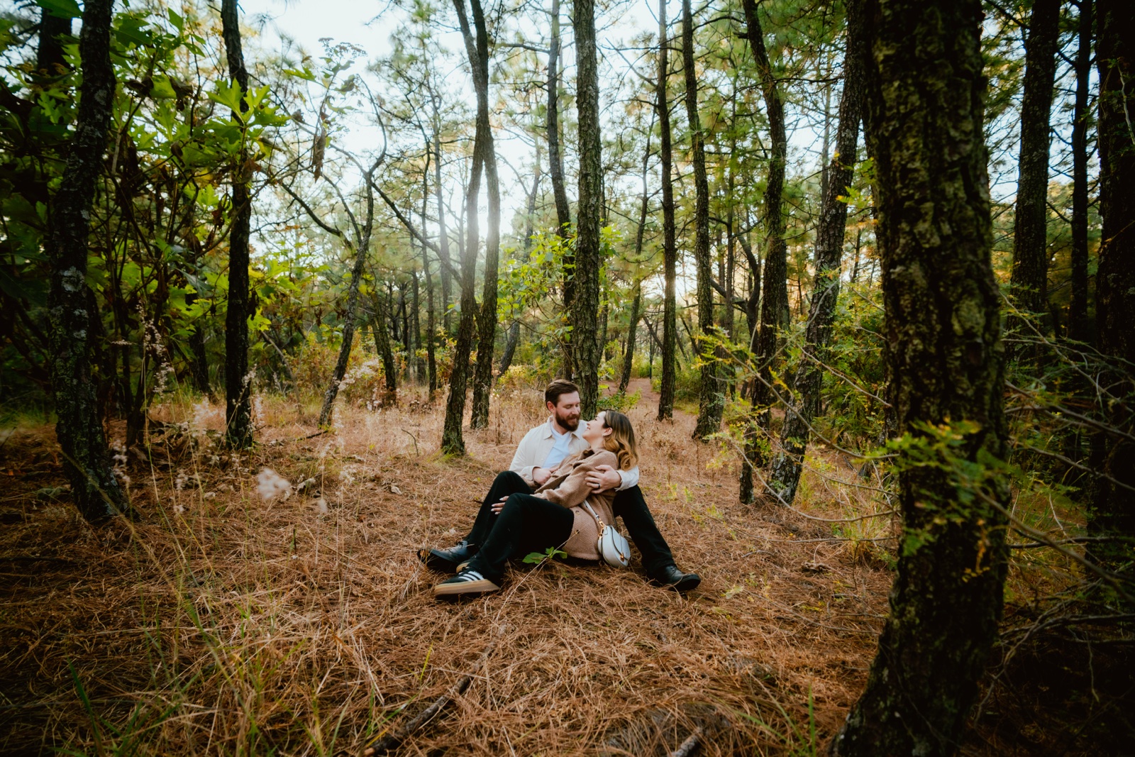 sesión de pareja sentada entre árboles en el bosque