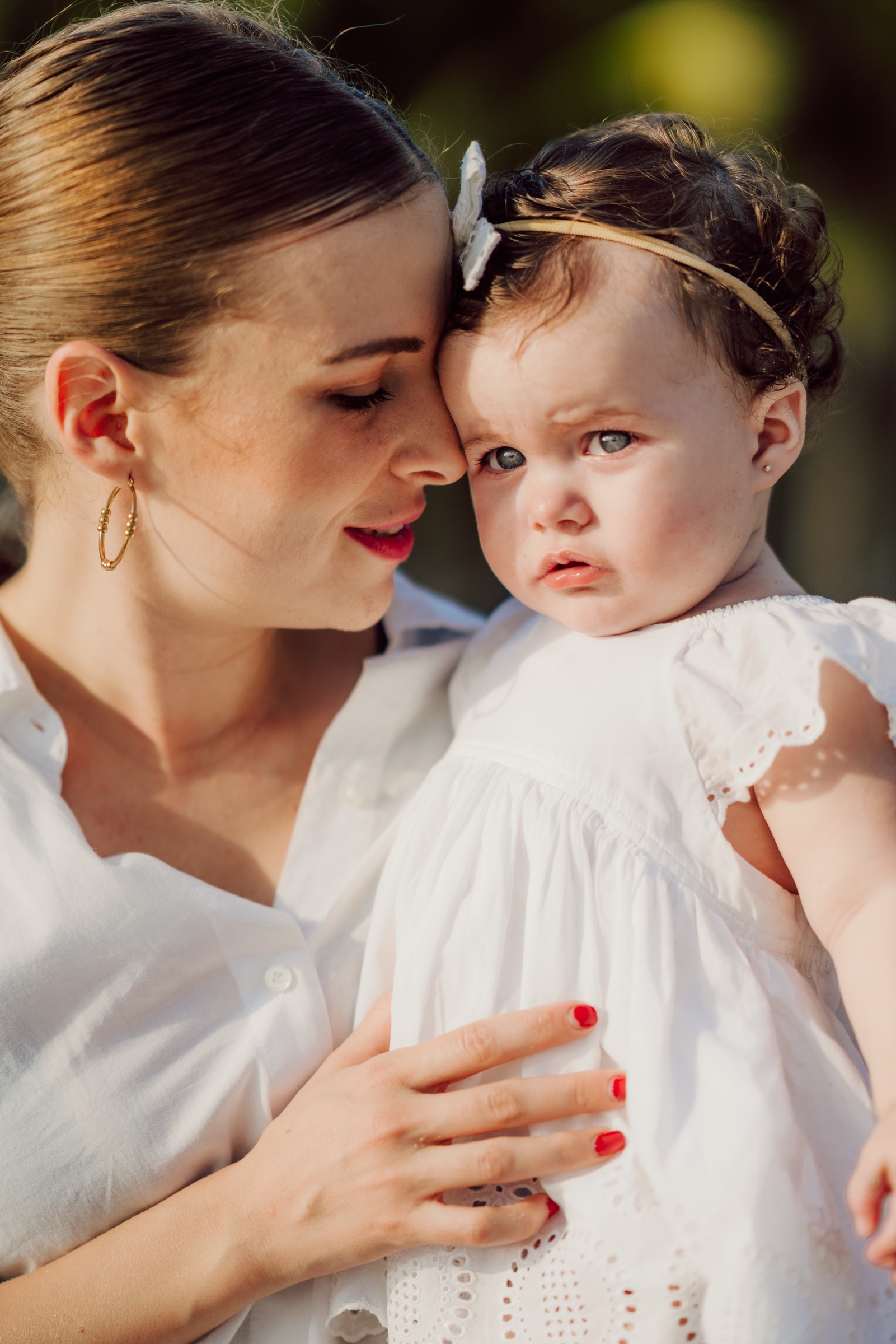 retrato familiar de una mujer sosteniendo a una niña con vestido blanco