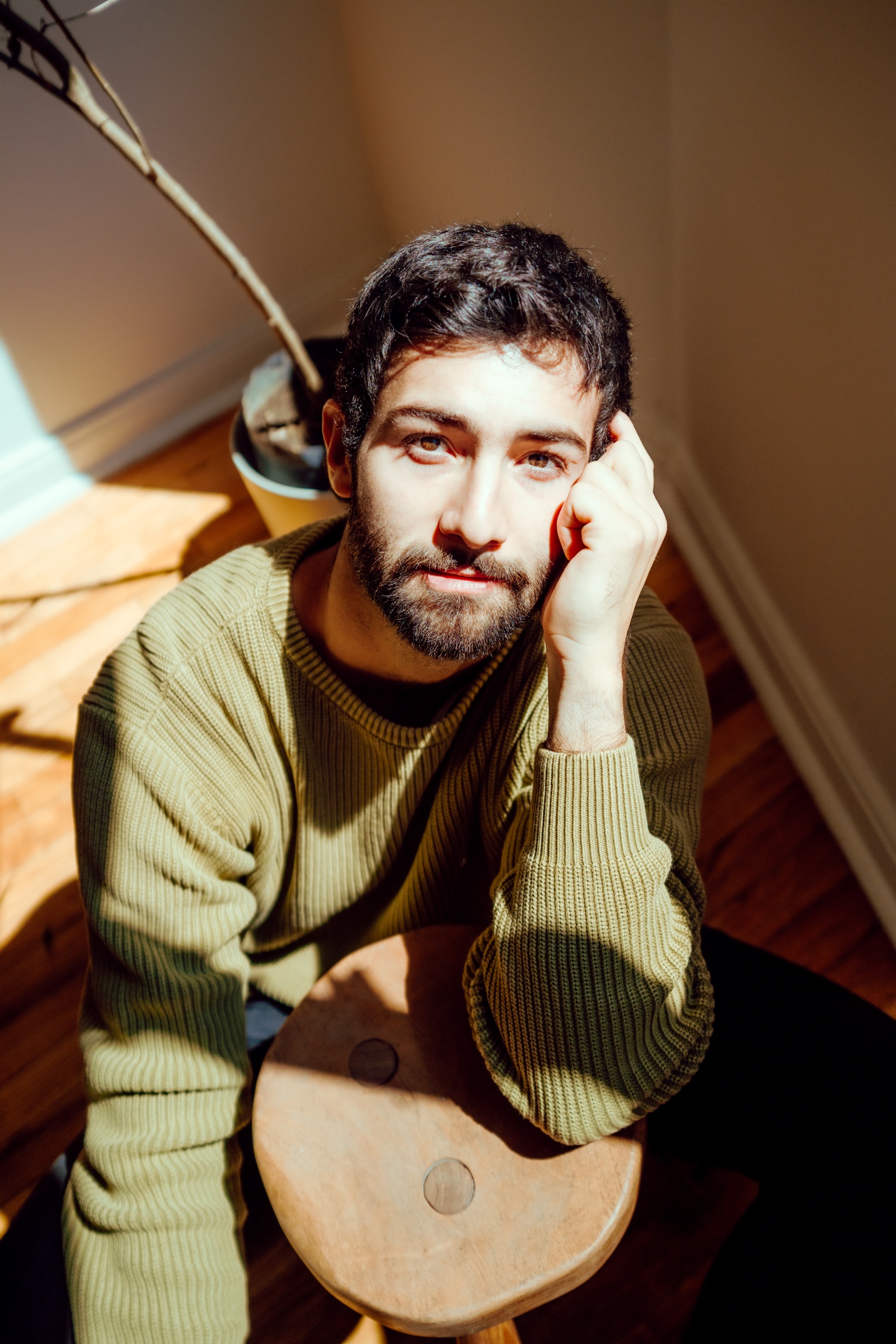 retrato de un hombre con suéter verde sentado junto a la ventana
