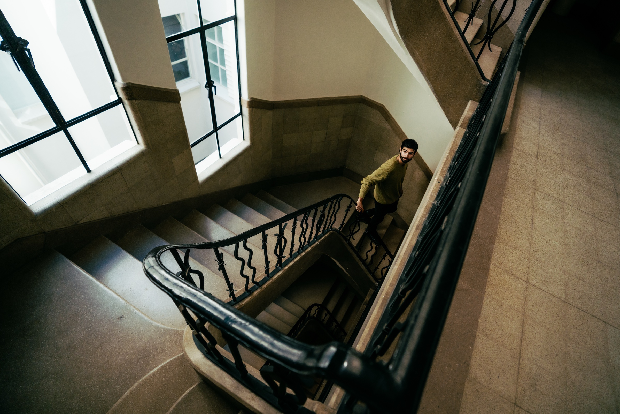 retrato de un hombre en una escalera iluminada por ventanales