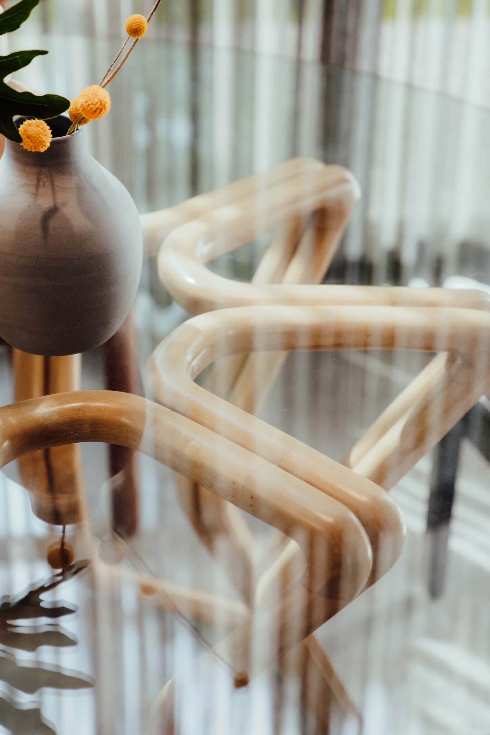 detalle de una mesa de cristal con base curva y florero