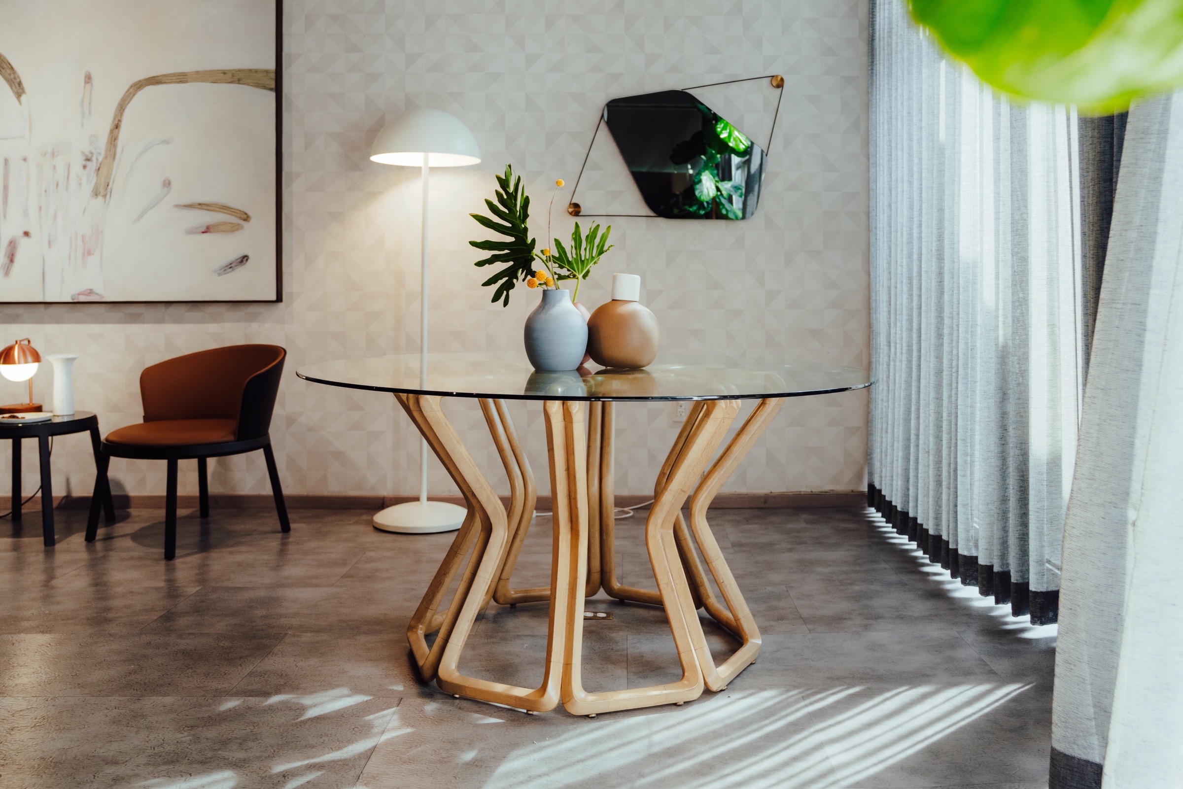 mesa de cristal con base de madera curva en un interior iluminado
