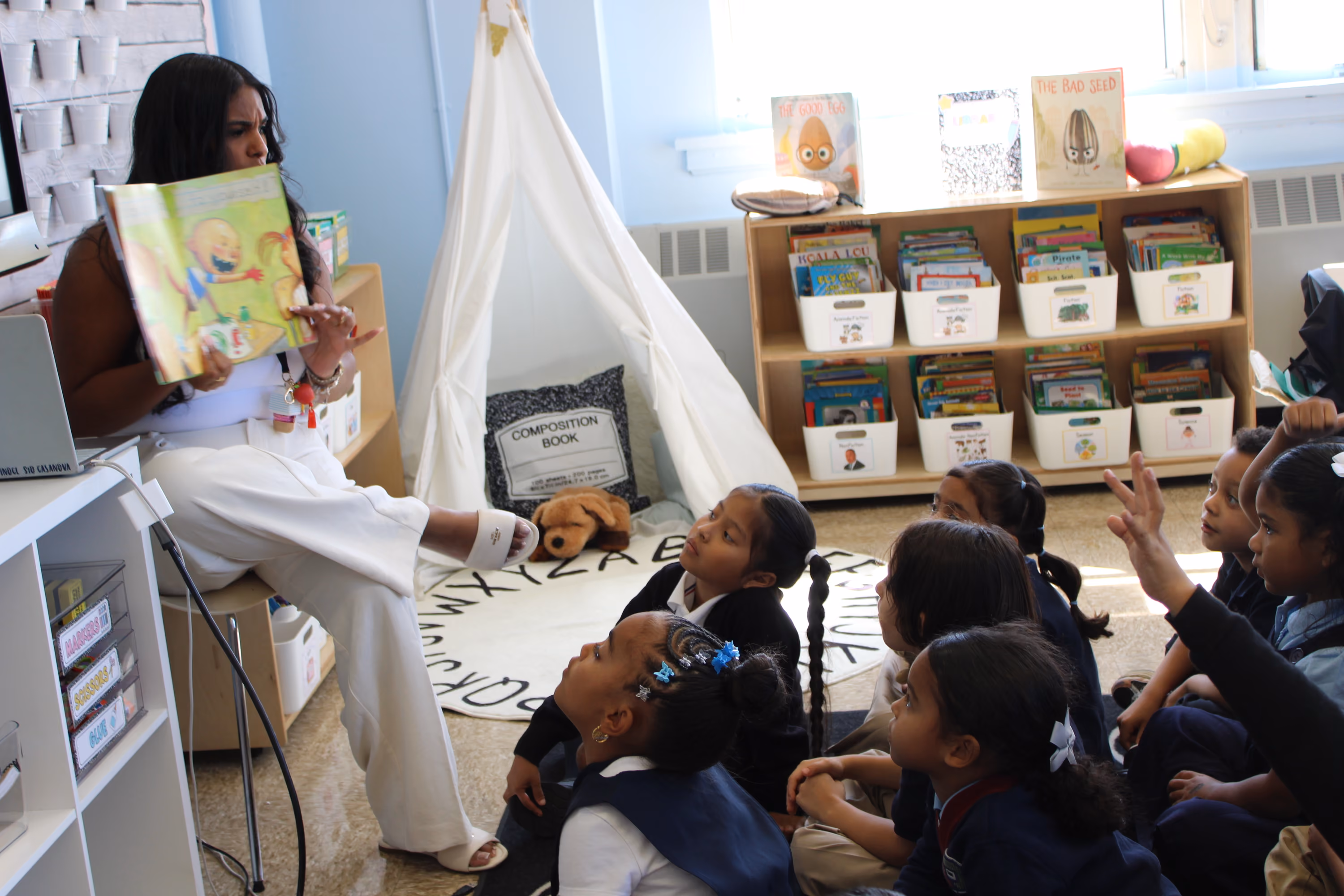 Teacher reads picture book aloud to elementary students on classroom floor