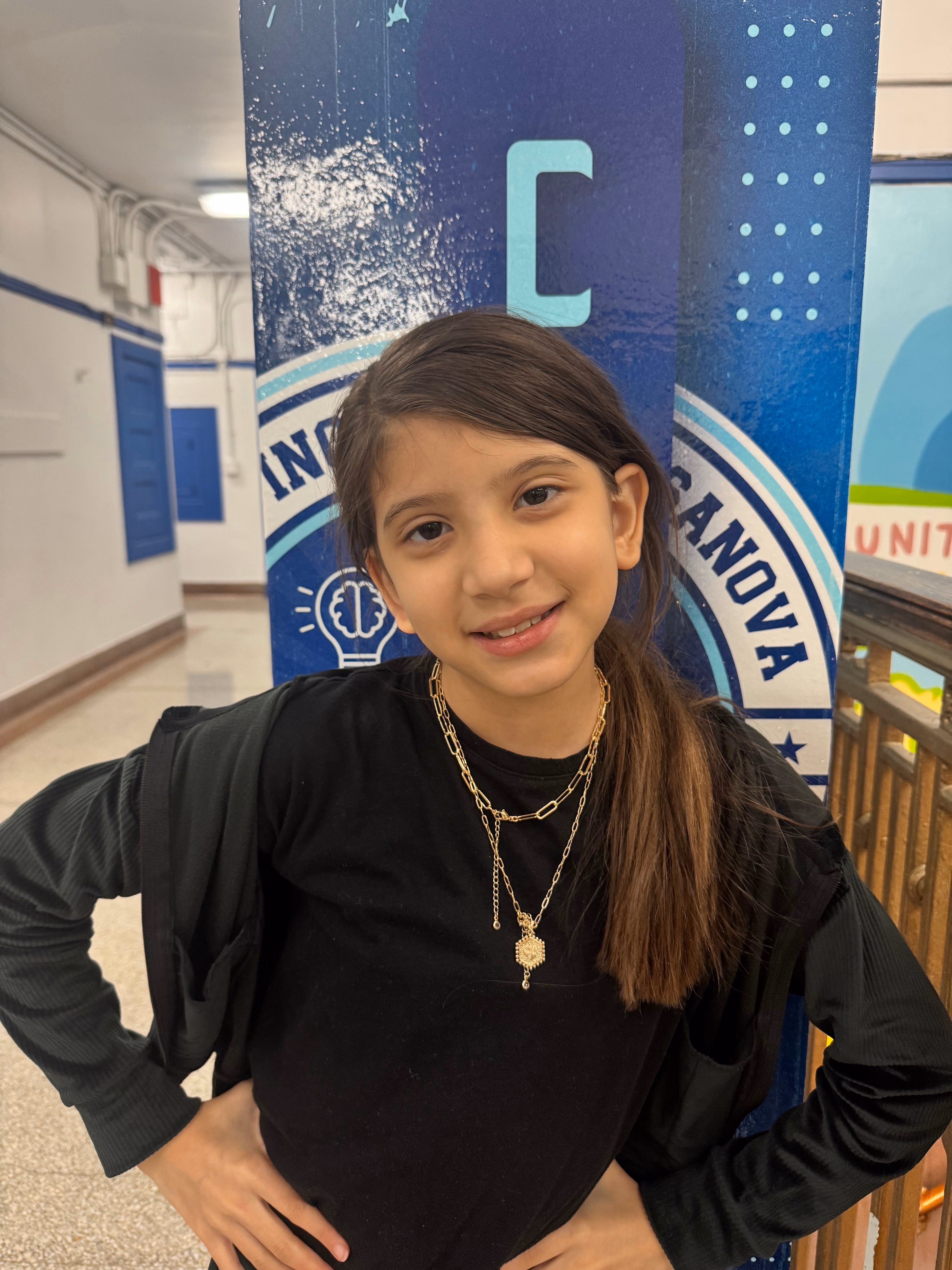 Student smiling in front of school banner at PS 62