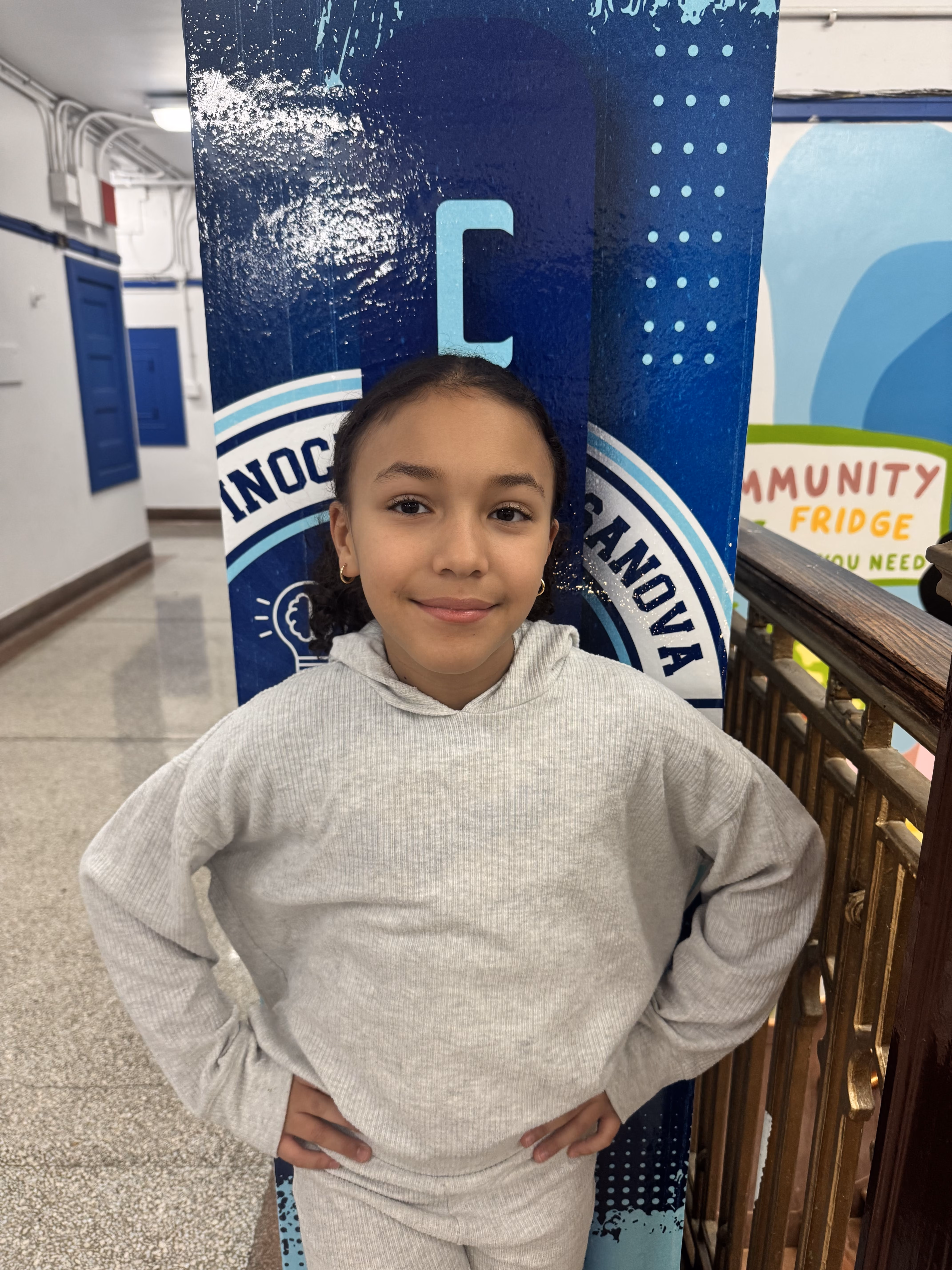 Student smiling in front of school banner at PS 62