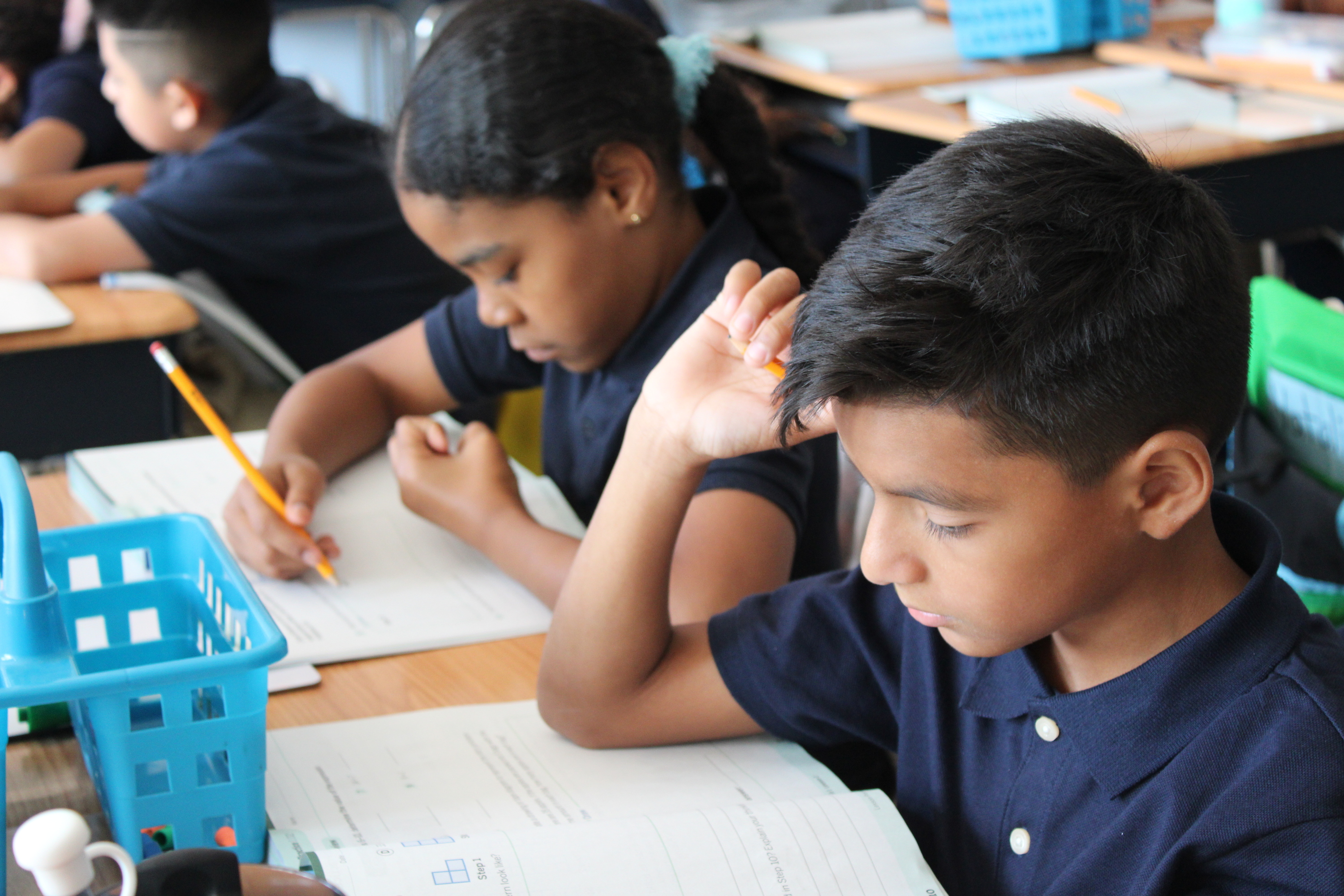 Students in uniform working on assignments at classroom desks