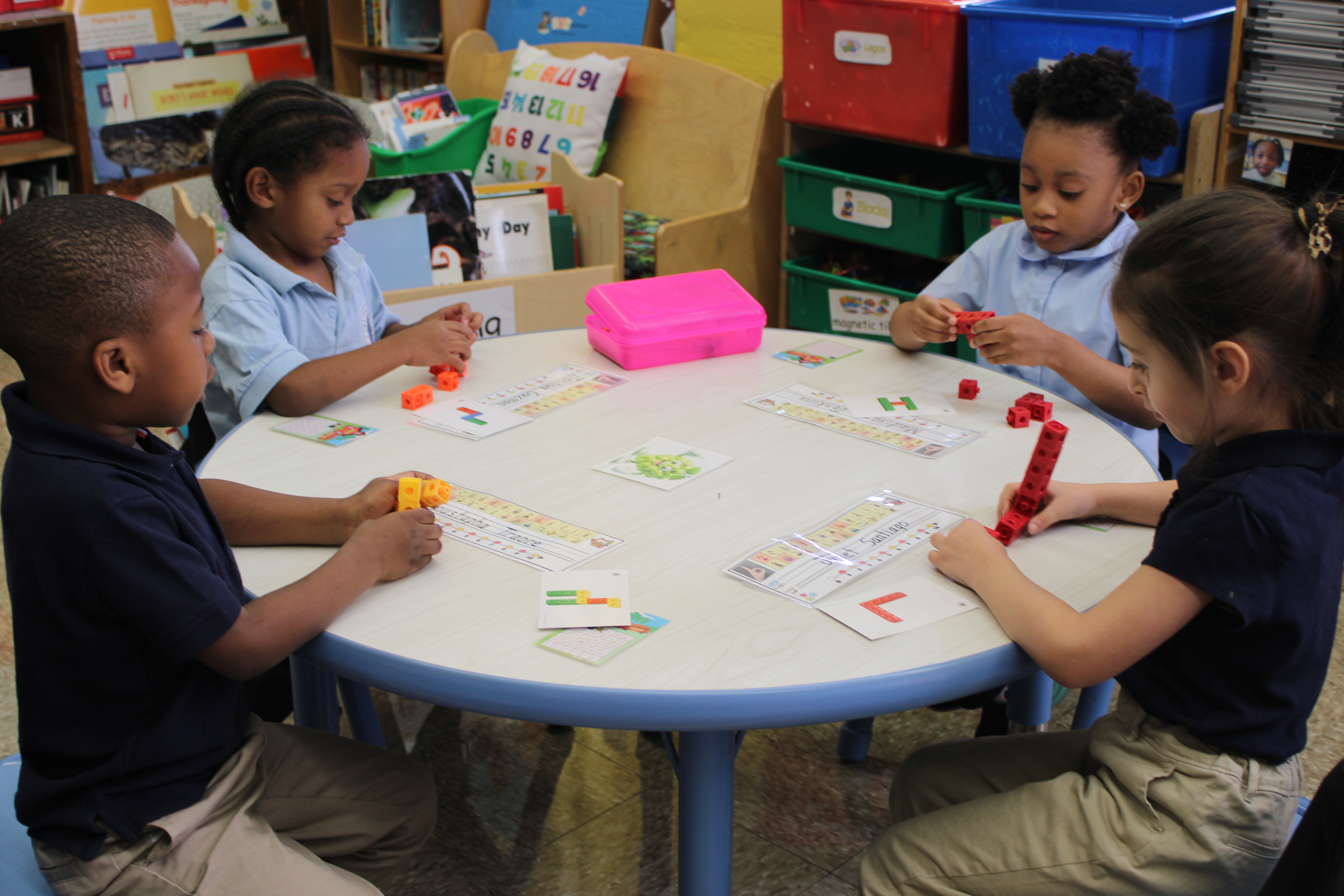 Four elementary students working with math manipulatives at classroom table
